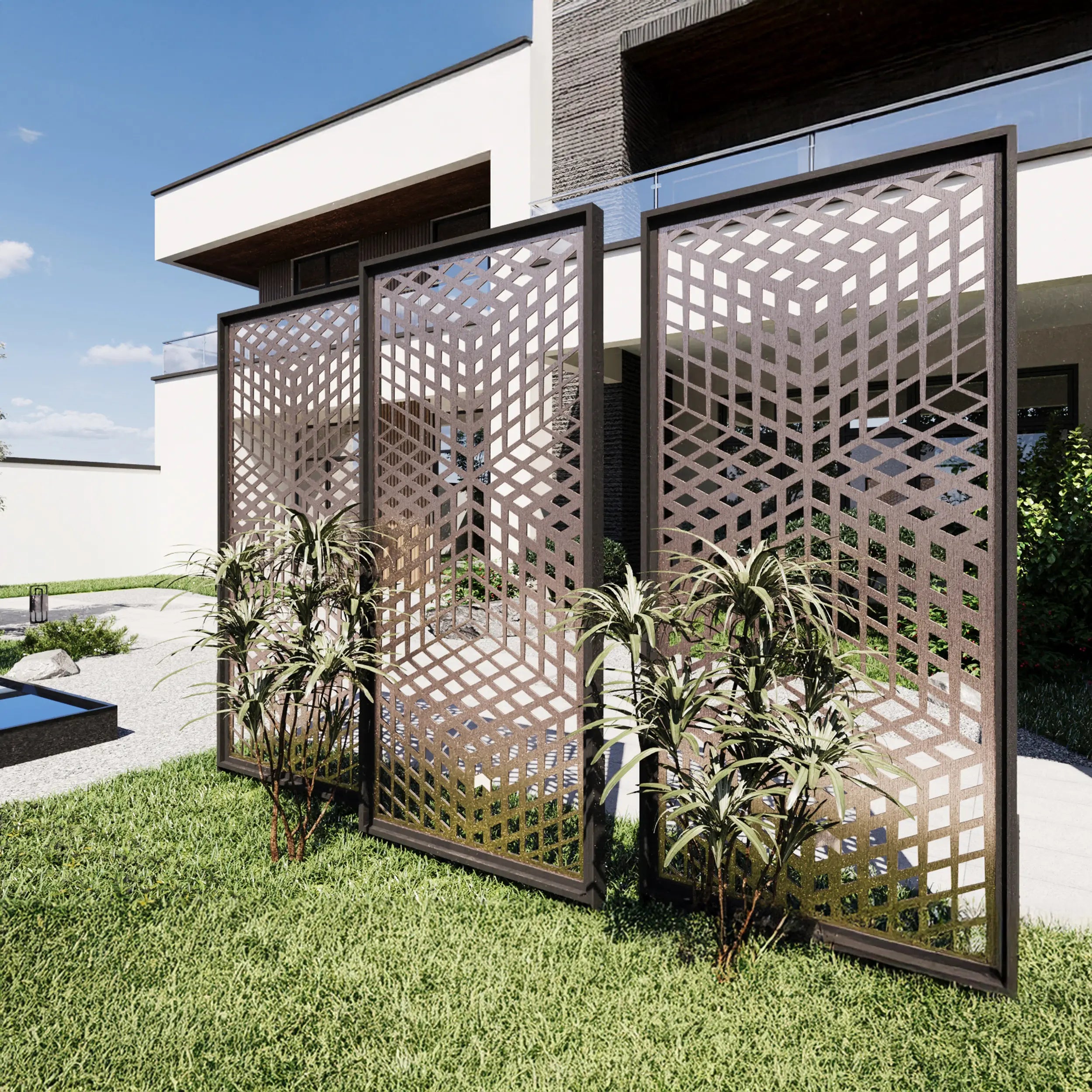 Three tall rectangular outdoor screen panels with geometric cutout patterns, installed on a grassy lawn in front of a modern house. Small plants are placed in front of the panels, and a blue sky is visible in the background.