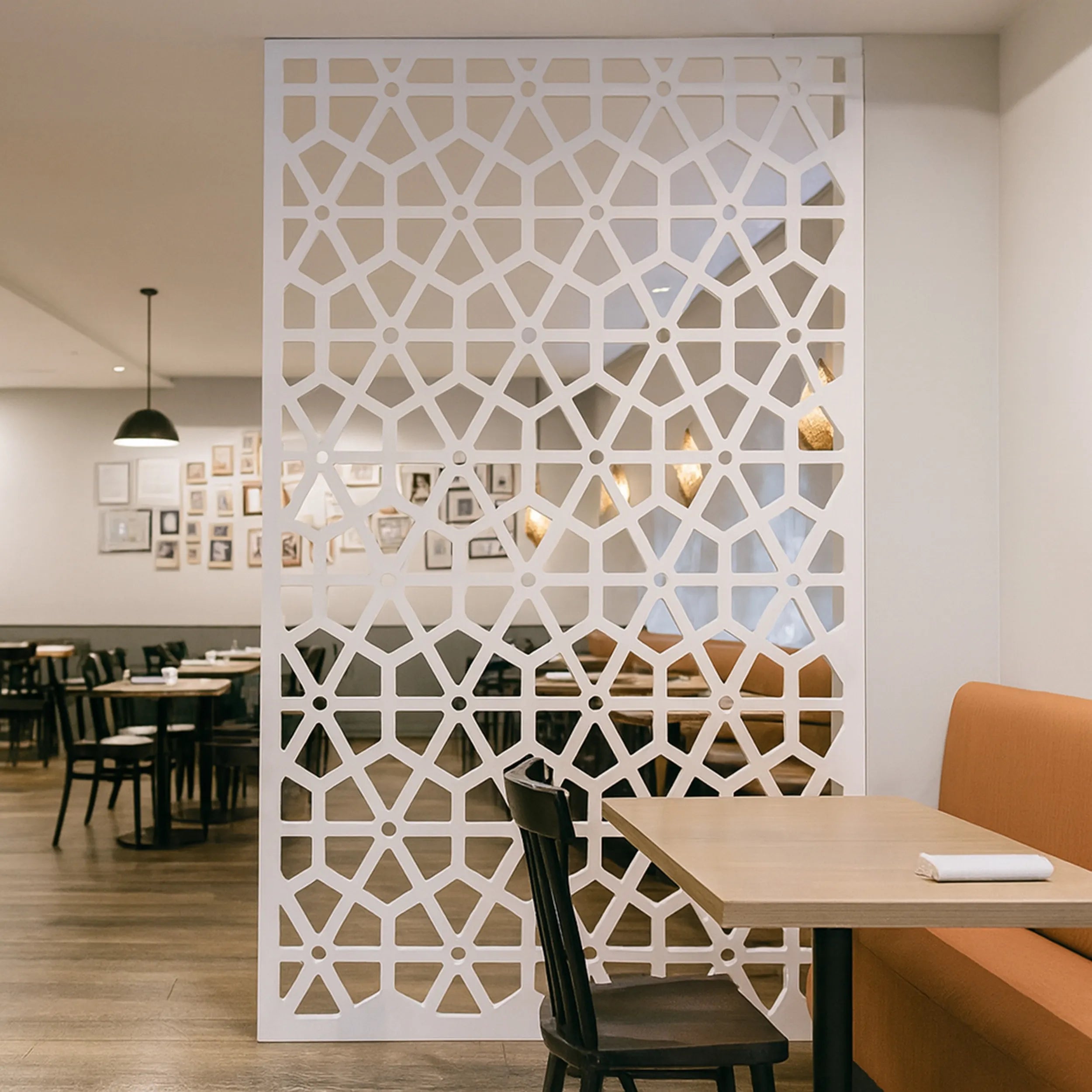 Decorative white screen in a restaurant setting with tables and chairs.