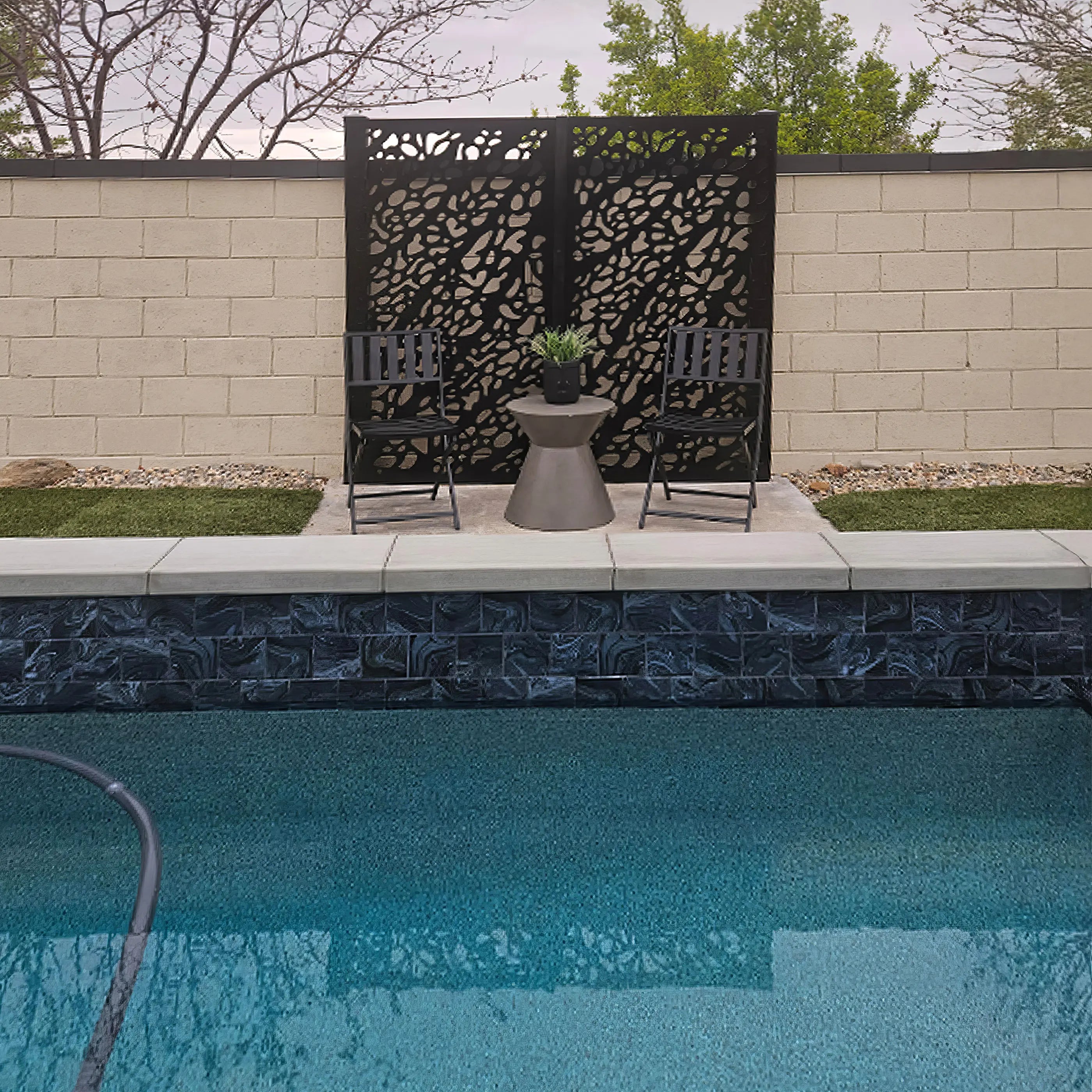 Pool area with decorative screen, chairs, and table near a brick wall.