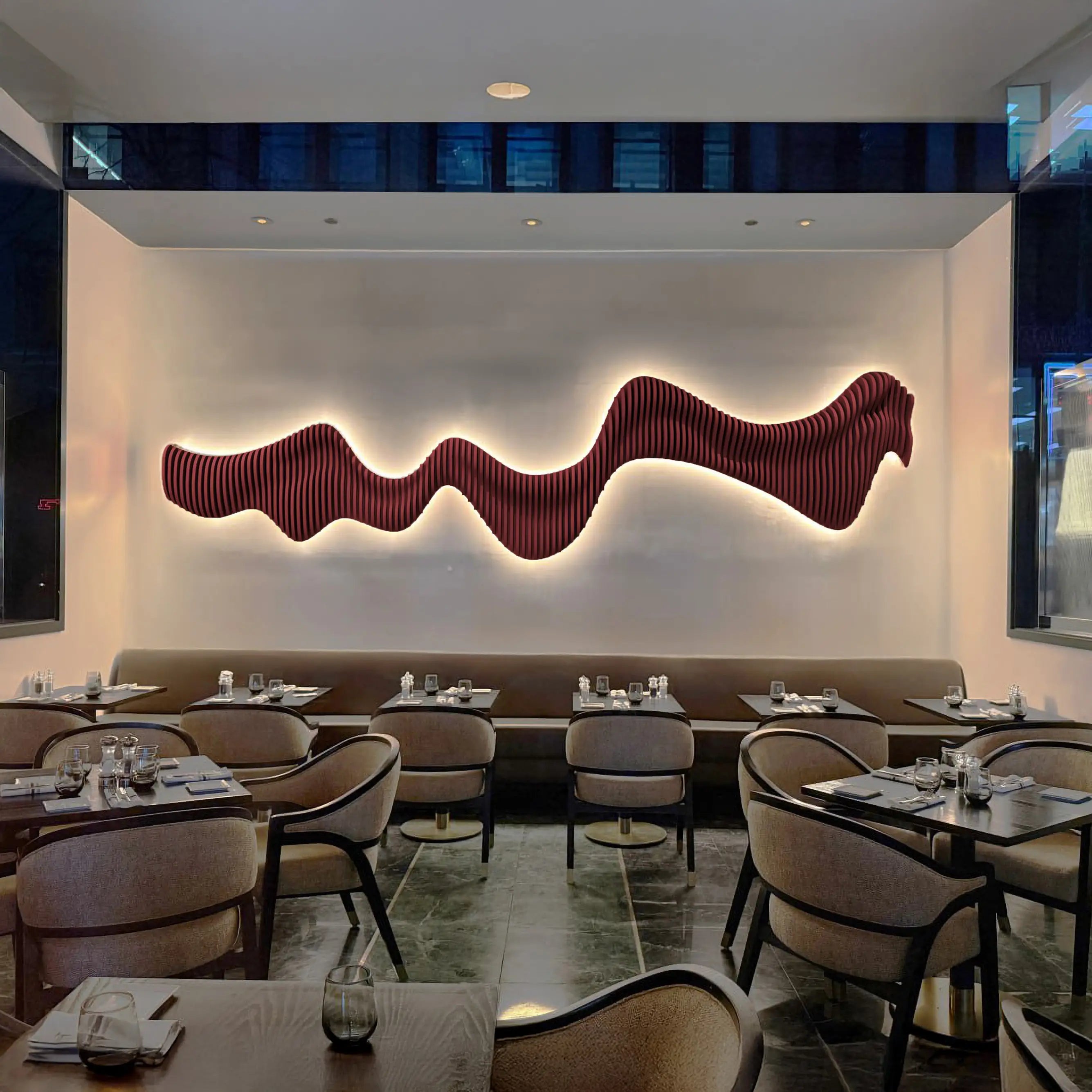 Modern restaurant interior with wavy red wall art and tables set for dining.