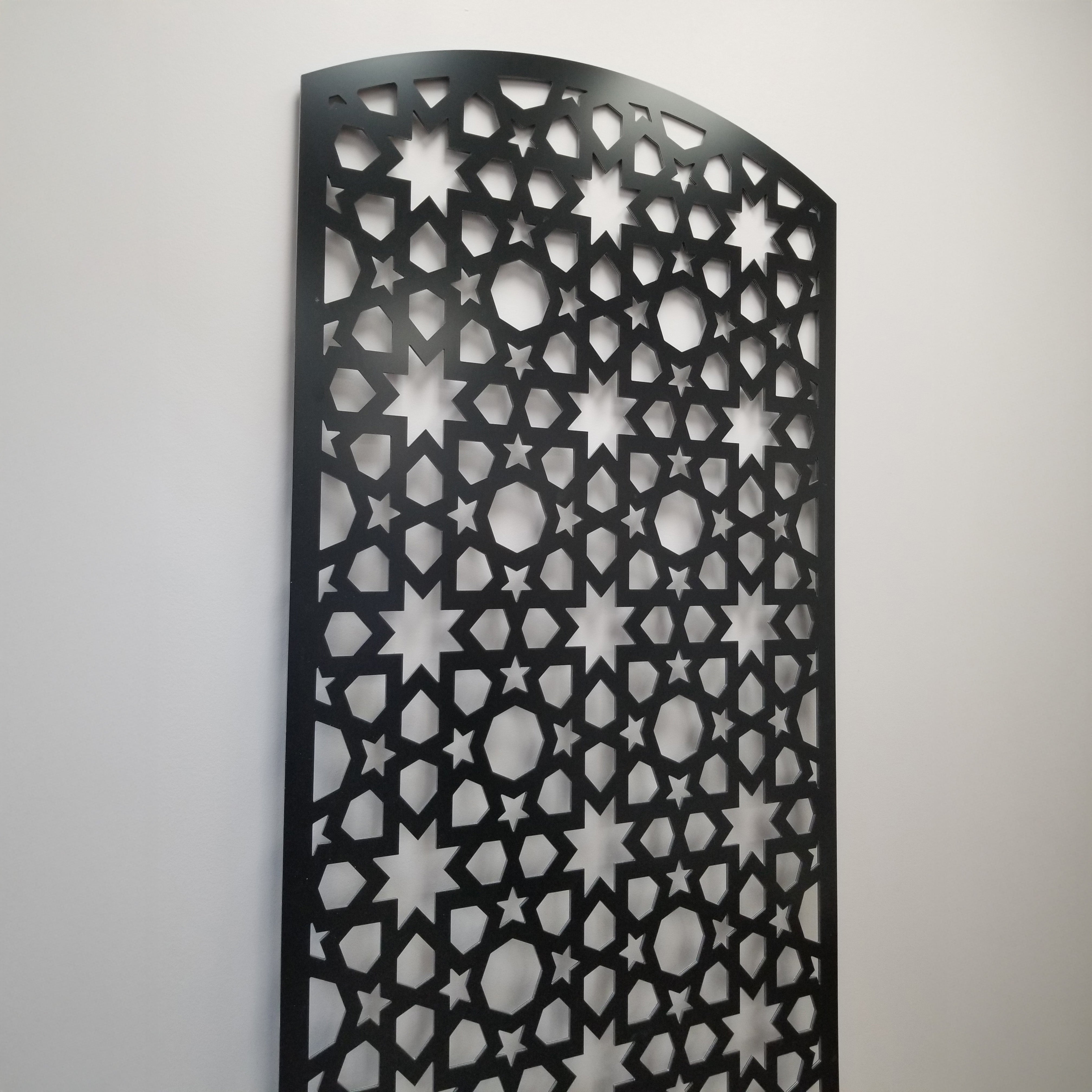 Decorative metal wall panel with star pattern on a plain background