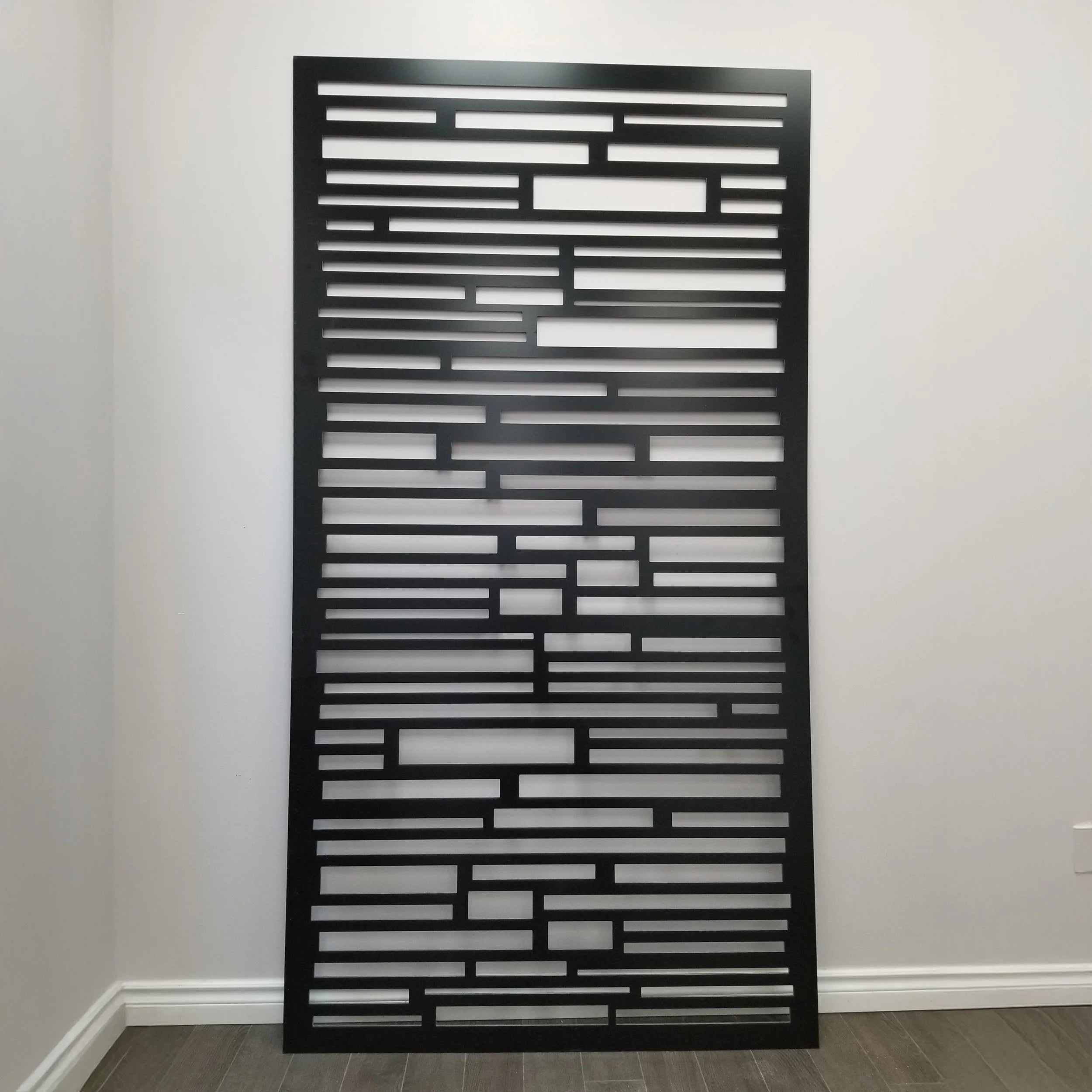 Decorative metal screen with geometric pattern against a plain wall.