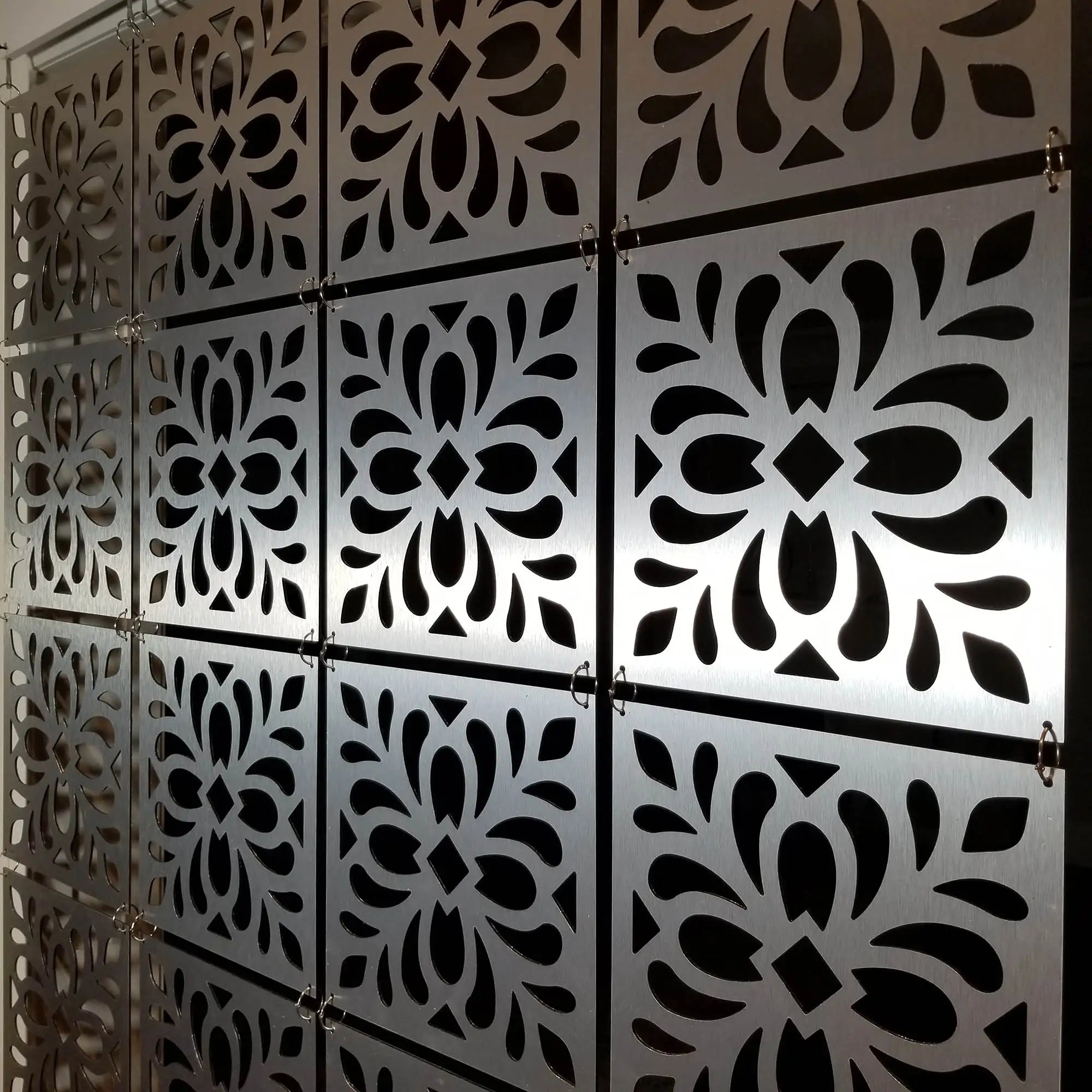Decorative metal panels with intricate cut-out patterns on a wall.