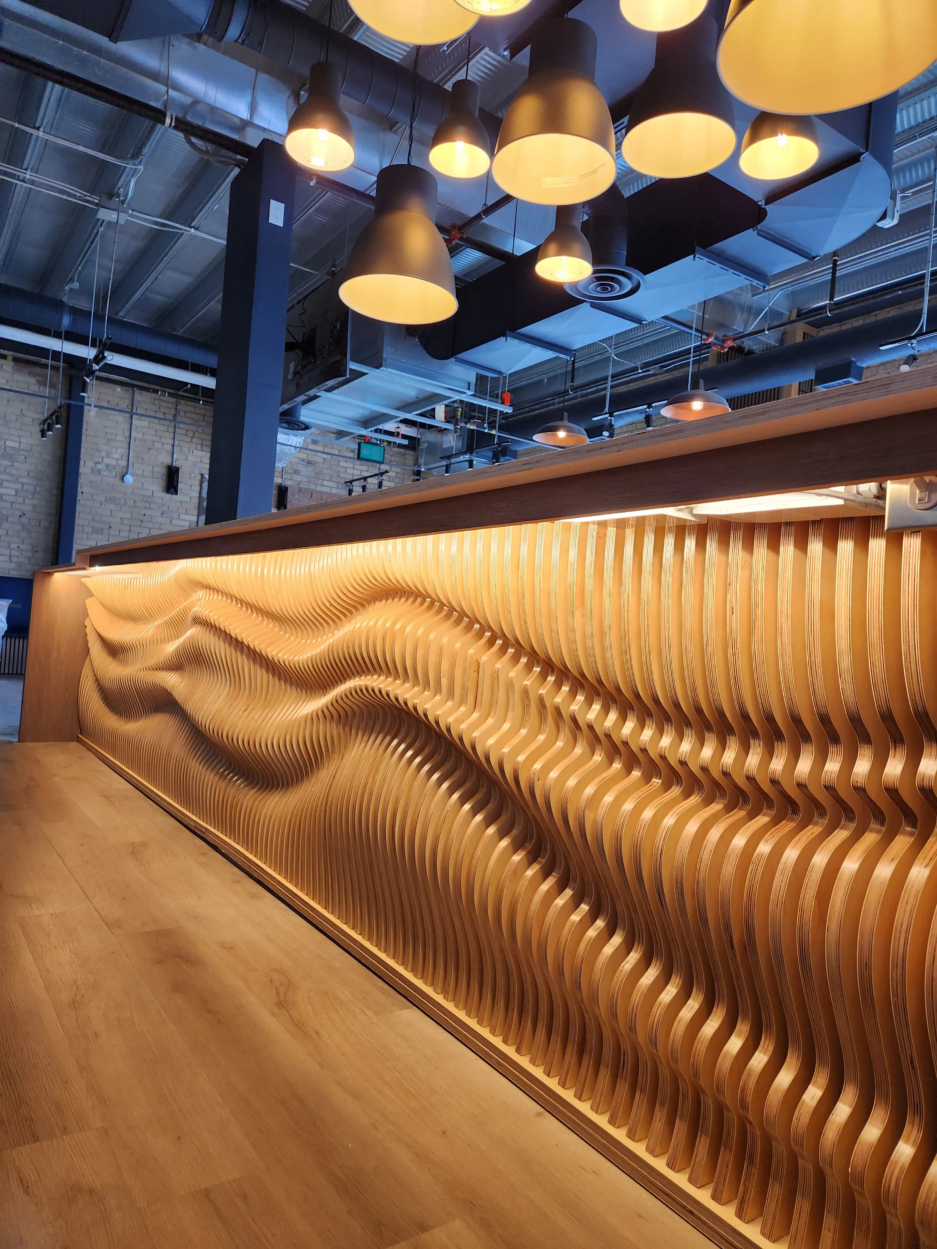 Wooden wave-patterned wall with hanging lights in a modern interior setting