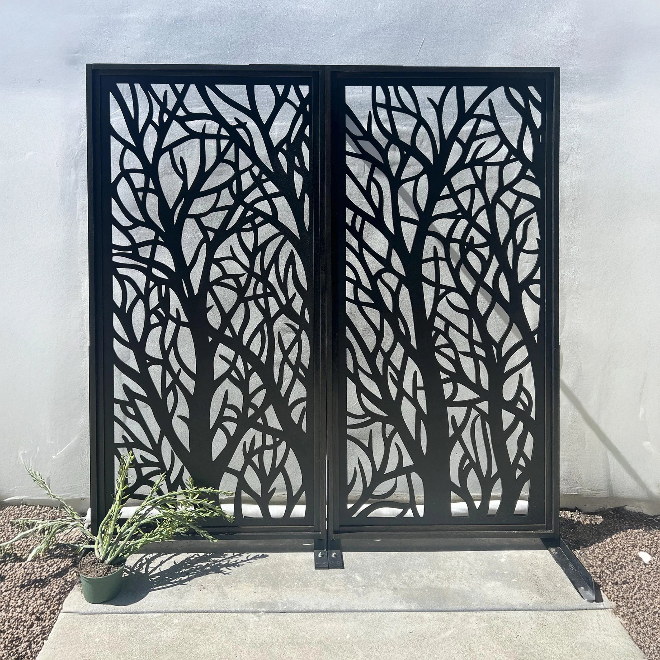 Decorative metal screen with tree branch pattern in front of a white wall