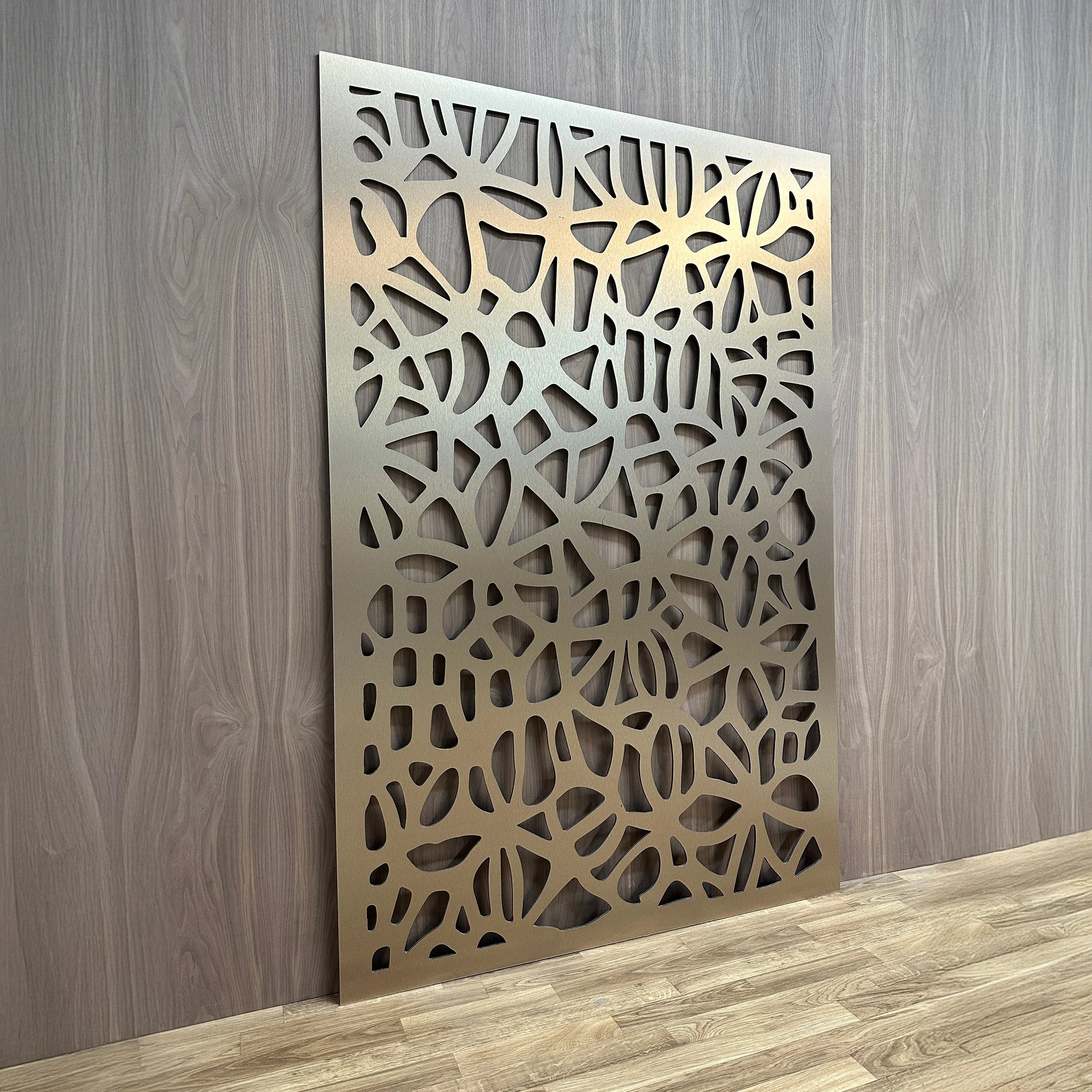 Decorative metal panel with intricate cut-out design on a wooden floor and wall.