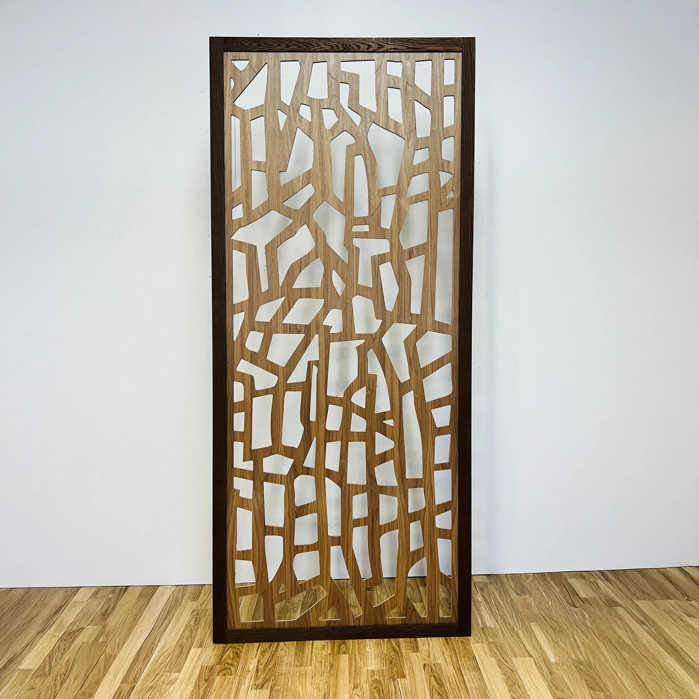 Wooden decorative screen with geometric pattern on a white wall.
