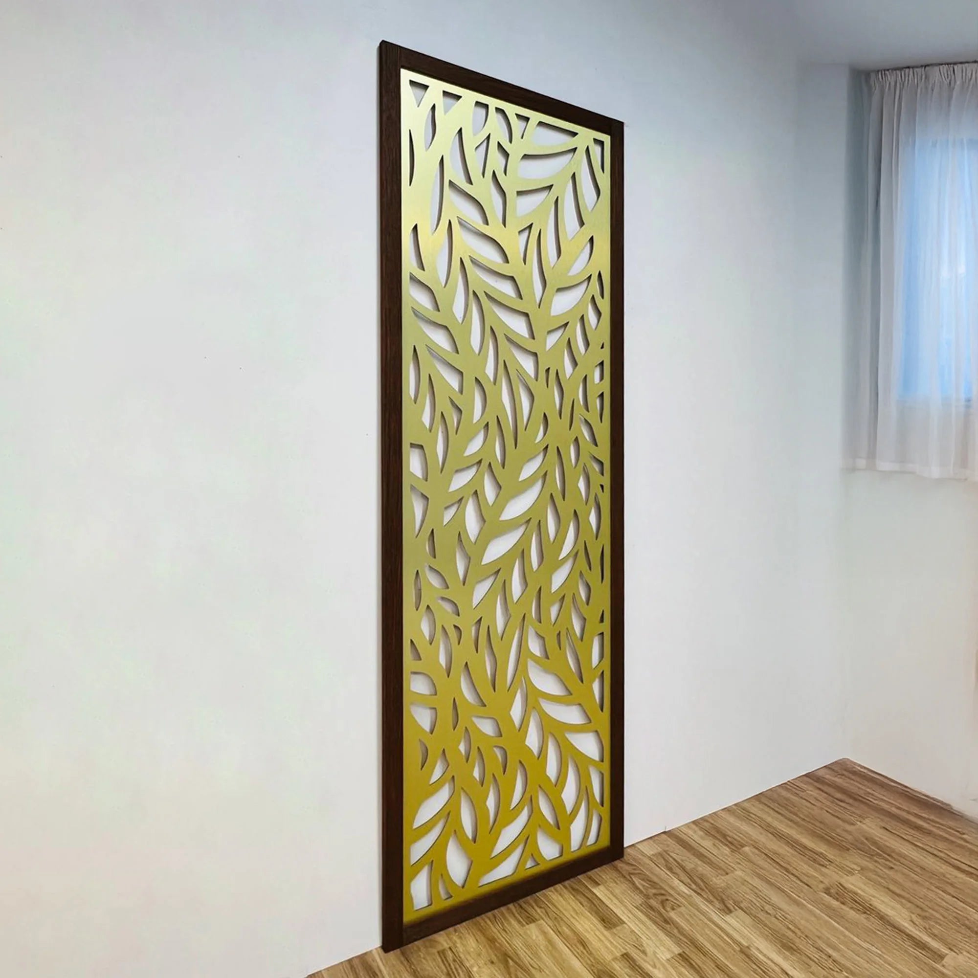 Decorative room divider with leaf pattern in a room with wooden floor and white walls.