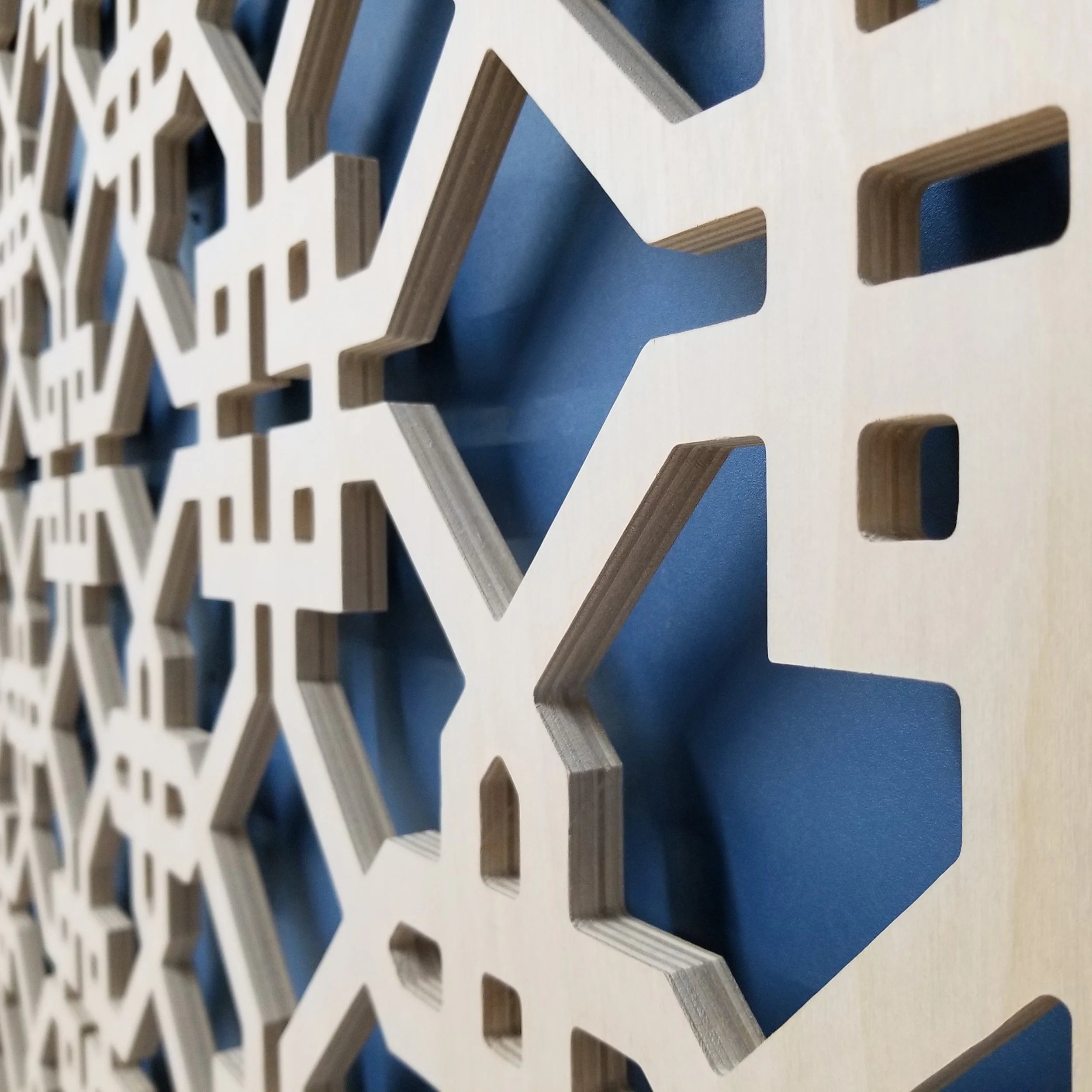 Close-up of a decorative wall panel with geometric cut-out patterns on a blue background
