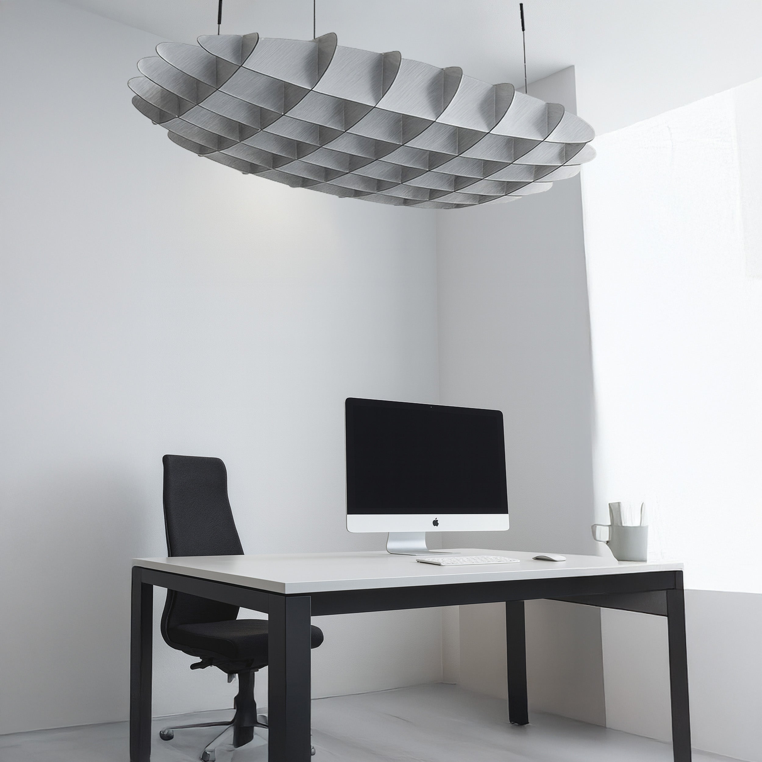 Modern office setup with a desk, chair, and computer monitor under a unique ceiling light fixture.