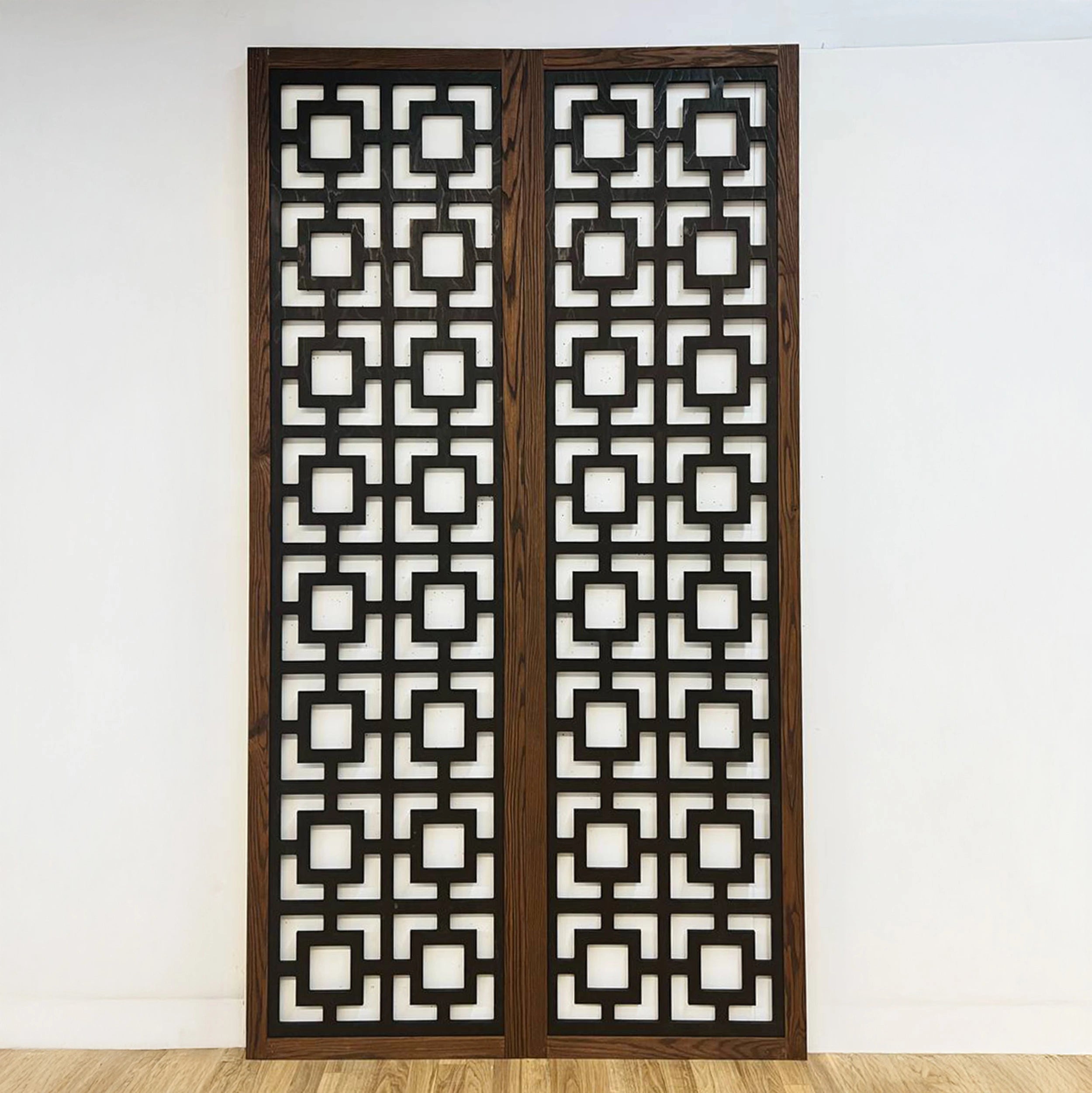 Decorative folding screen with geometric pattern on a white wall.