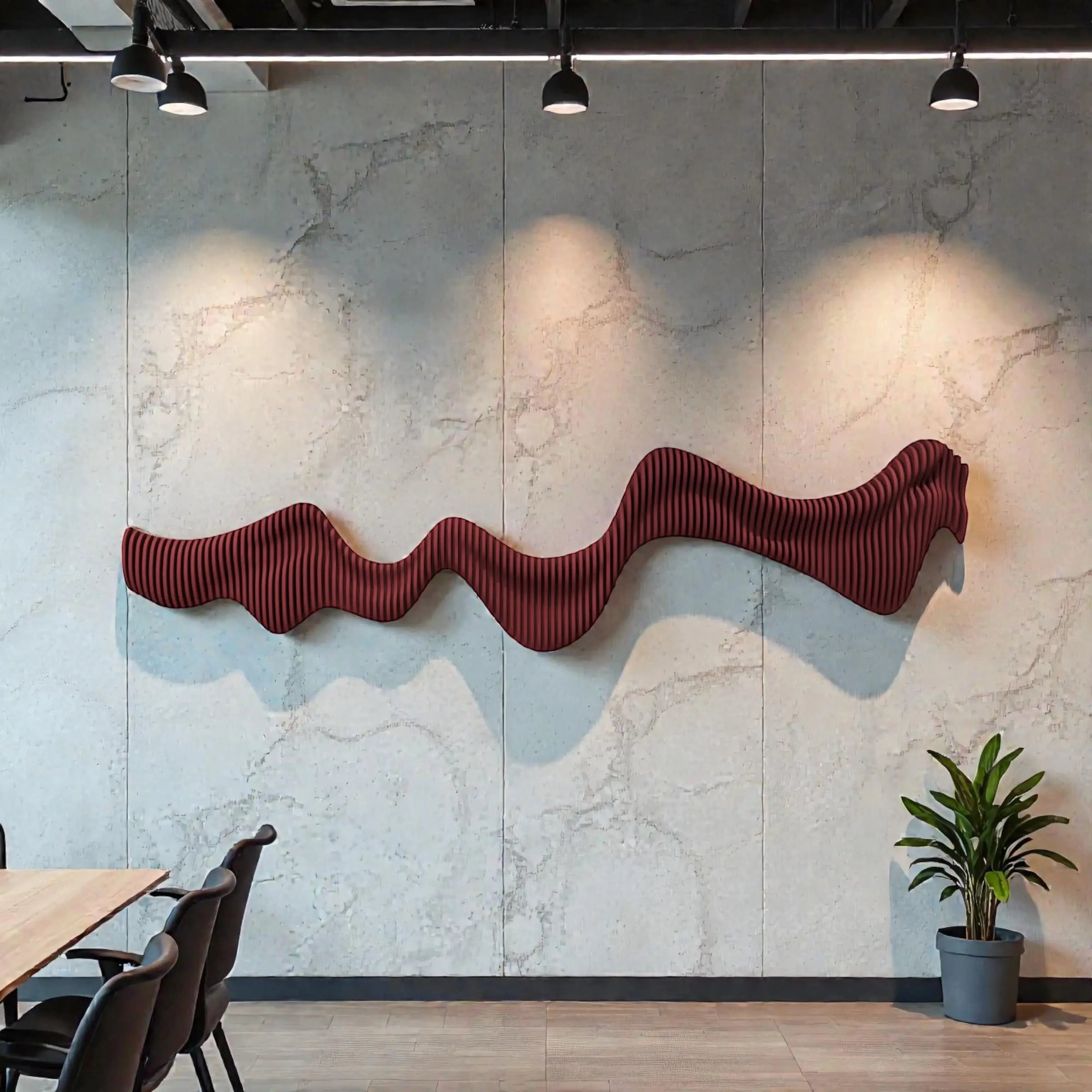 Wavy red decorative wall art on a textured gray wall with a plant and table in the foreground.