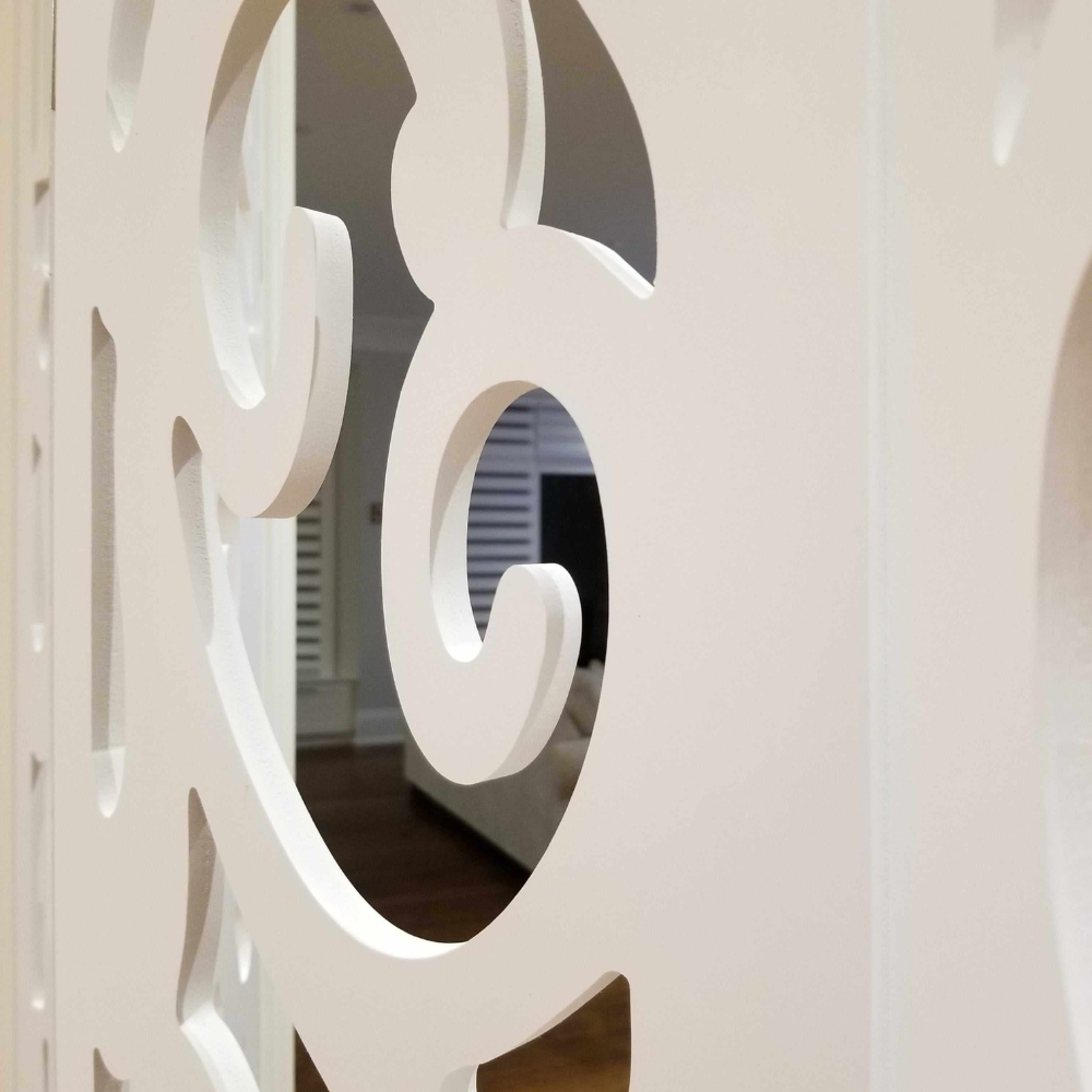 Decorative white screen with intricate cut-out patterns in a room setting.