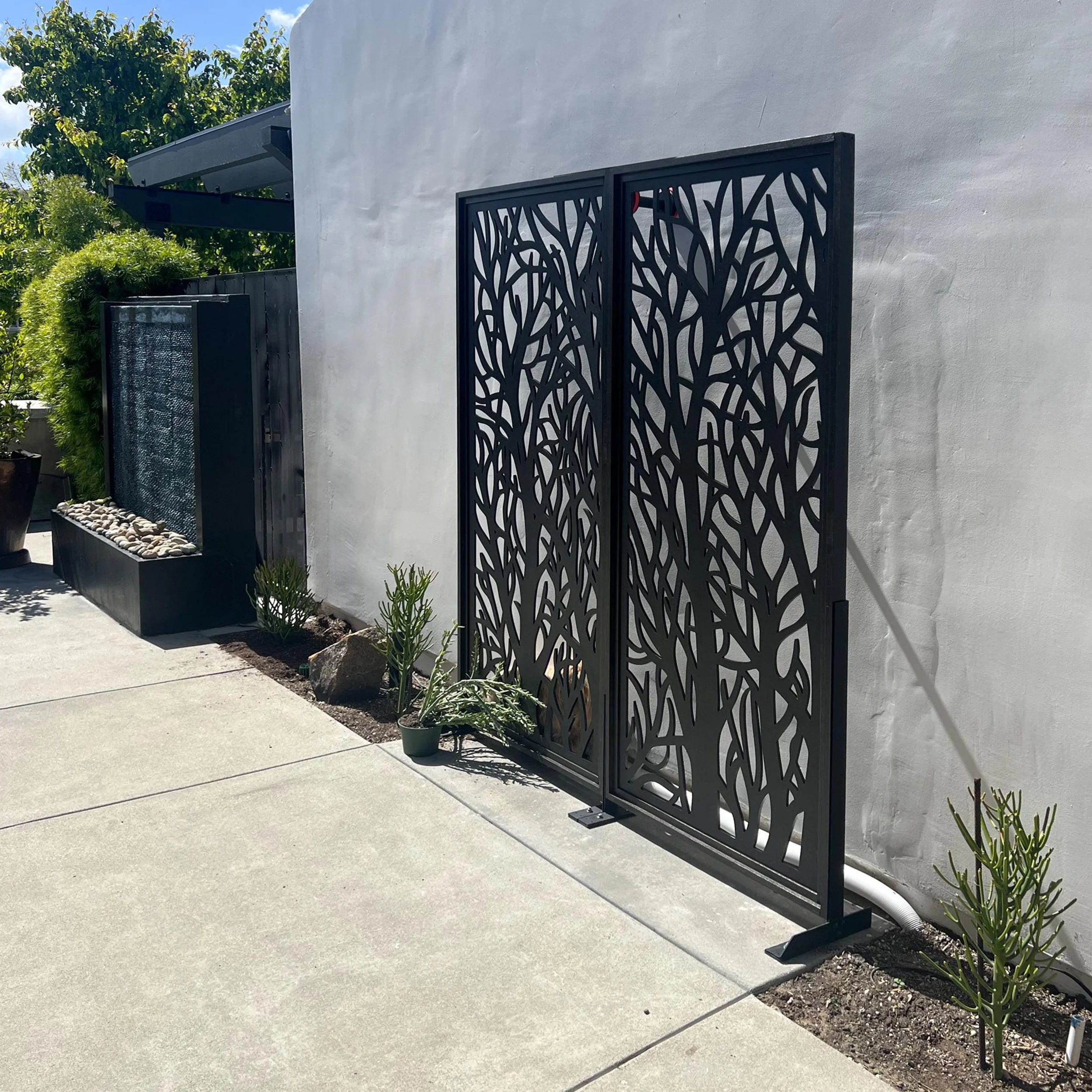 Decorative metal screen with tree branch pattern against a white wall.