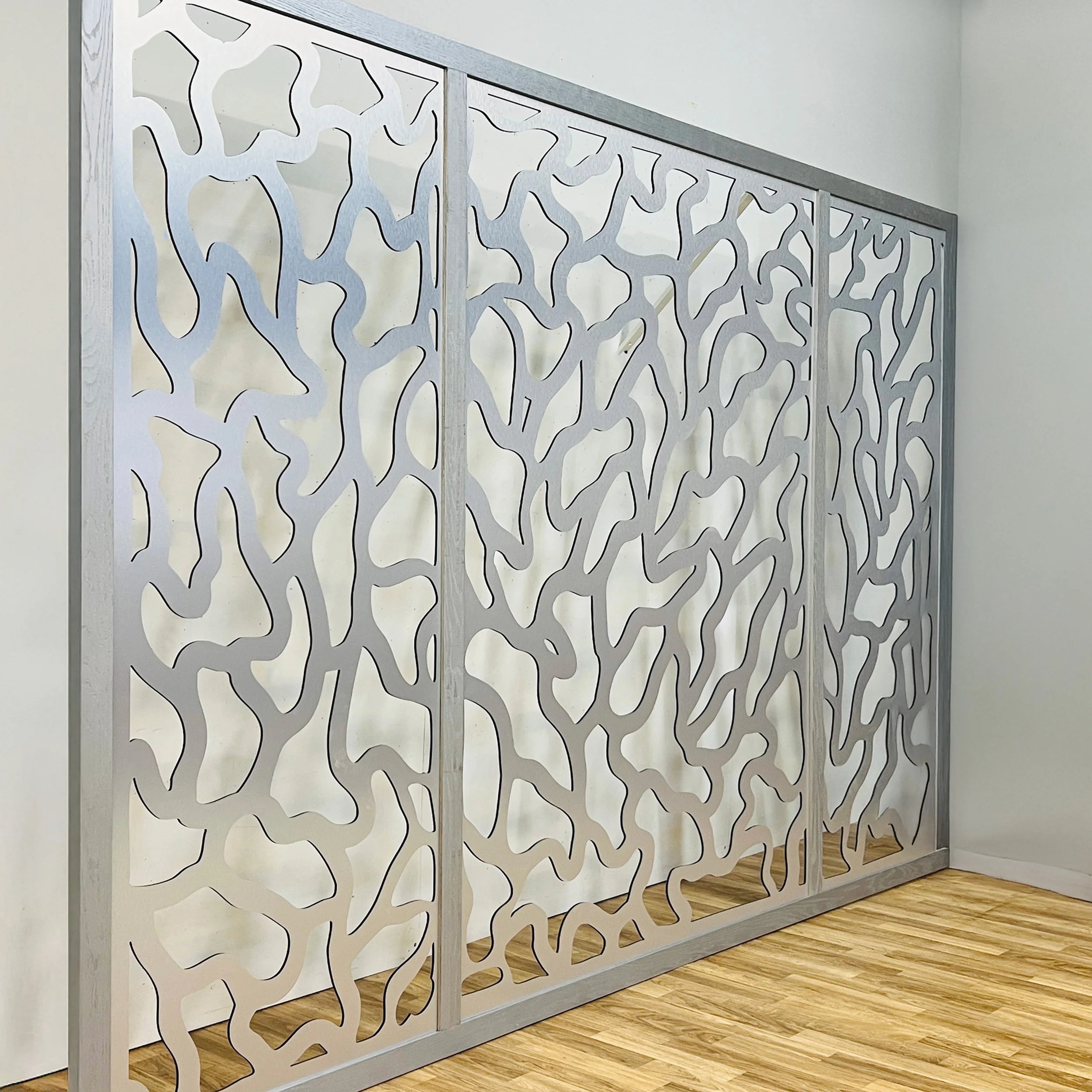 Decorative wall panel with intricate cut-out patterns in a room with wooden flooring.