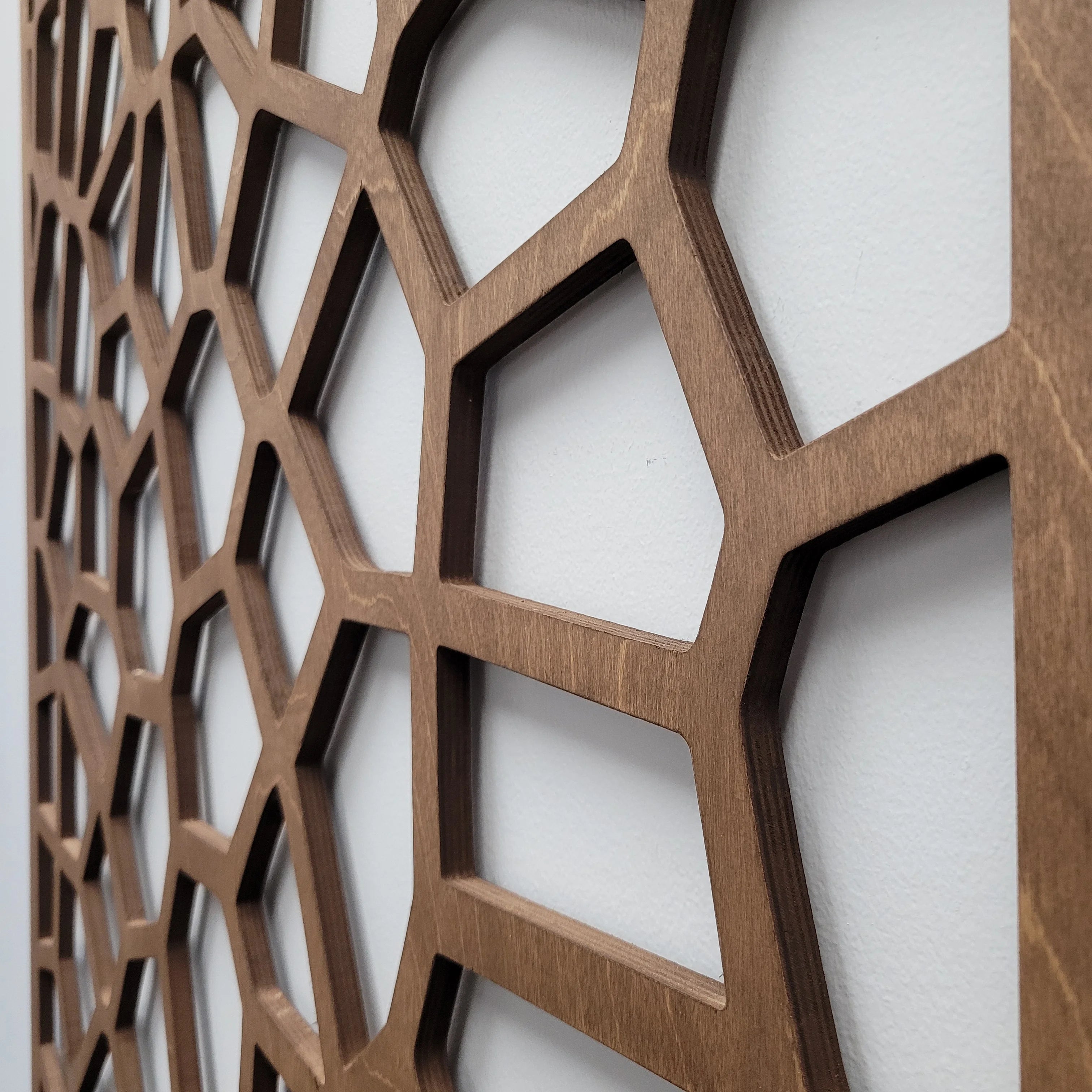 Close-up of a wooden decorative panel with geometric cut-out design on a white background