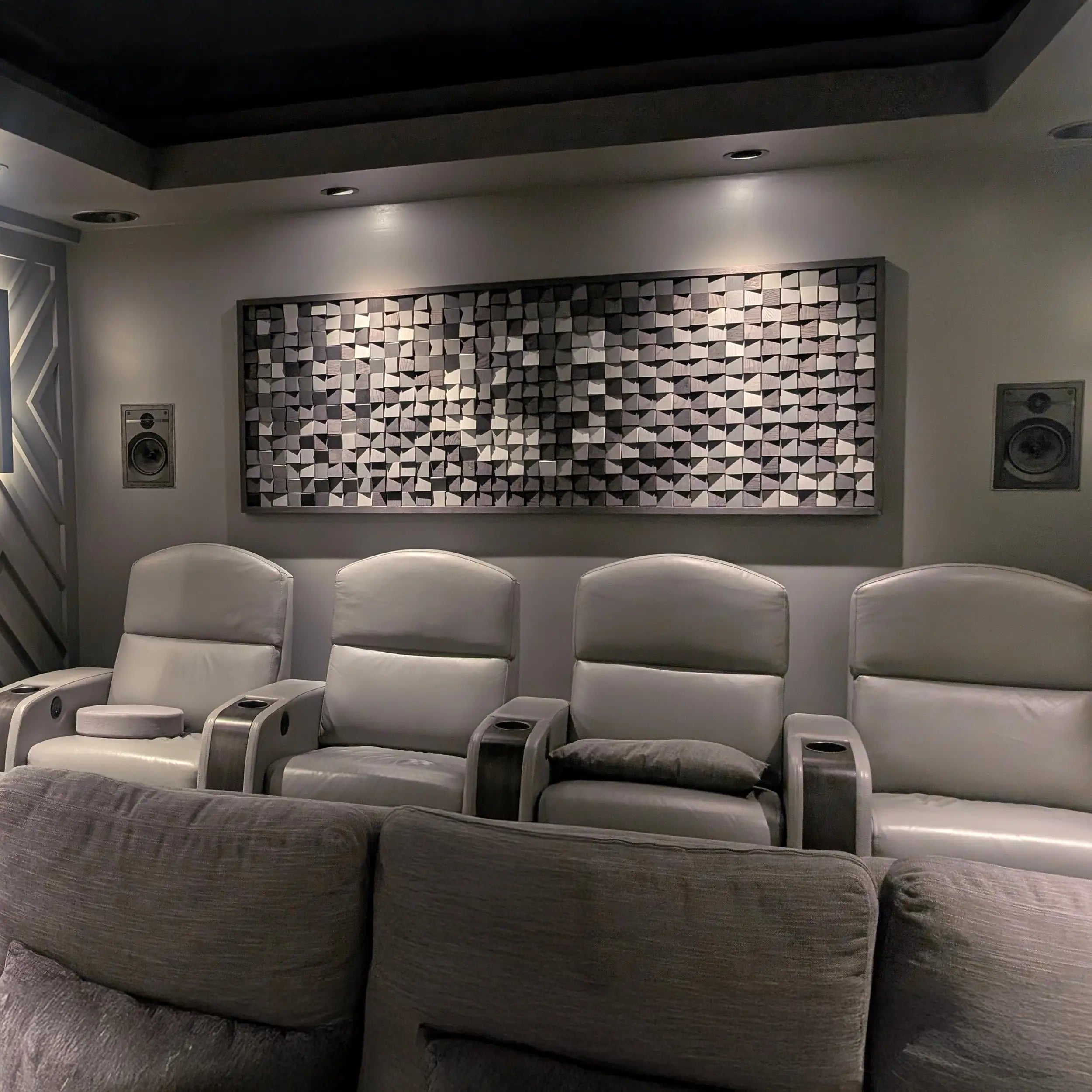 Modern home theater with gray recliner chairs and decorative wall art.