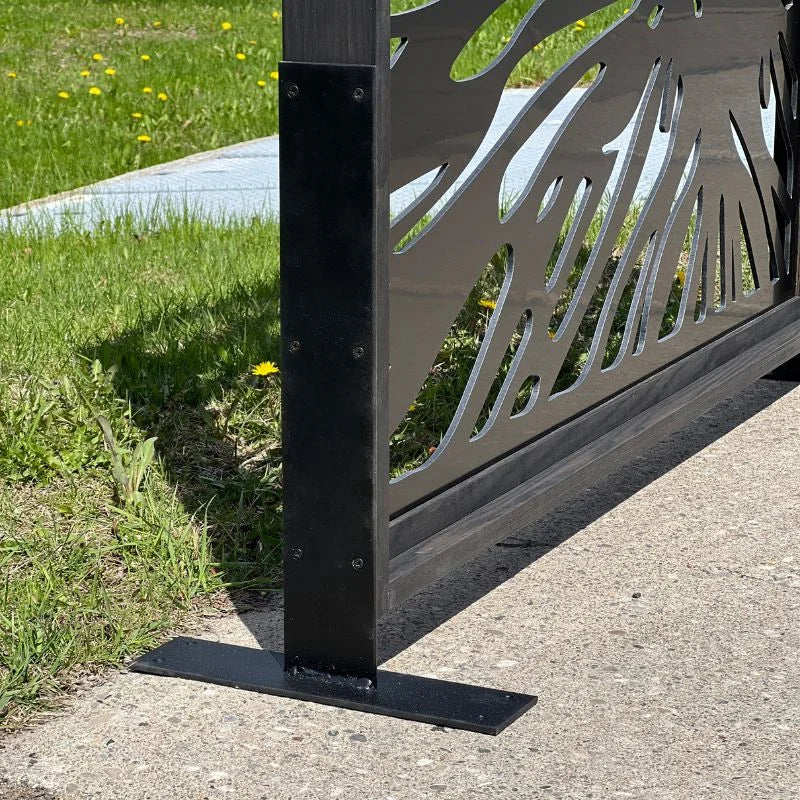 Metallic outdoor privacy panel with decorative design on a grassy area