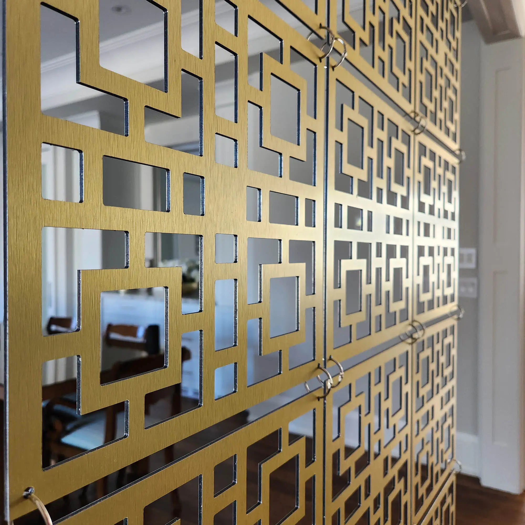 Decorative gold metal screen with geometric pattern in a room setting