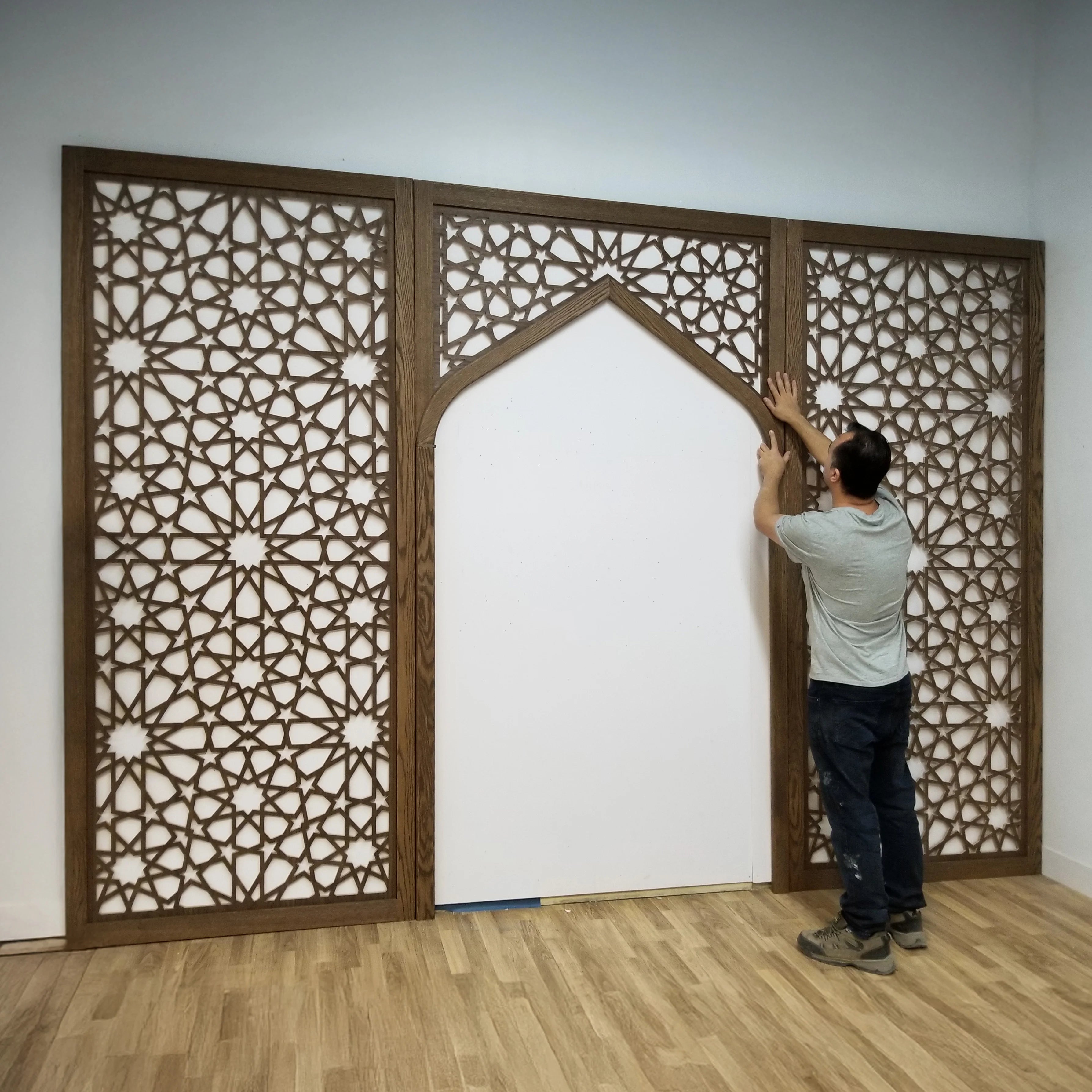 Person installing decorative wooden panels with intricate patterns on a wall.