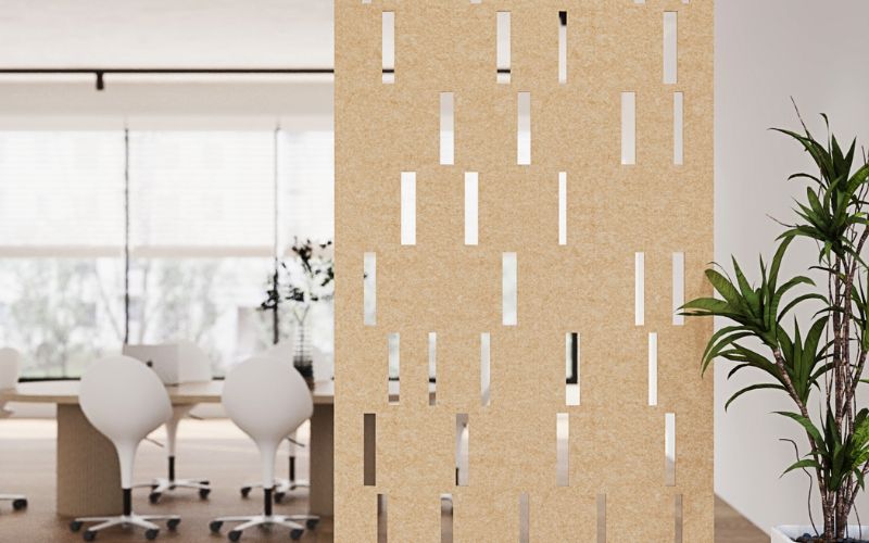 Beige perforated room divider in an office setting with white chairs and a plant.
