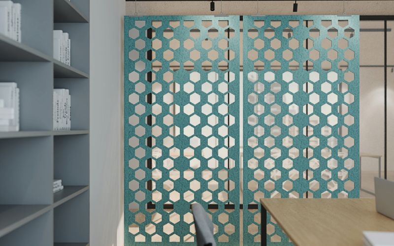 Decorative screen with geometric pattern in a room with shelves and a table.