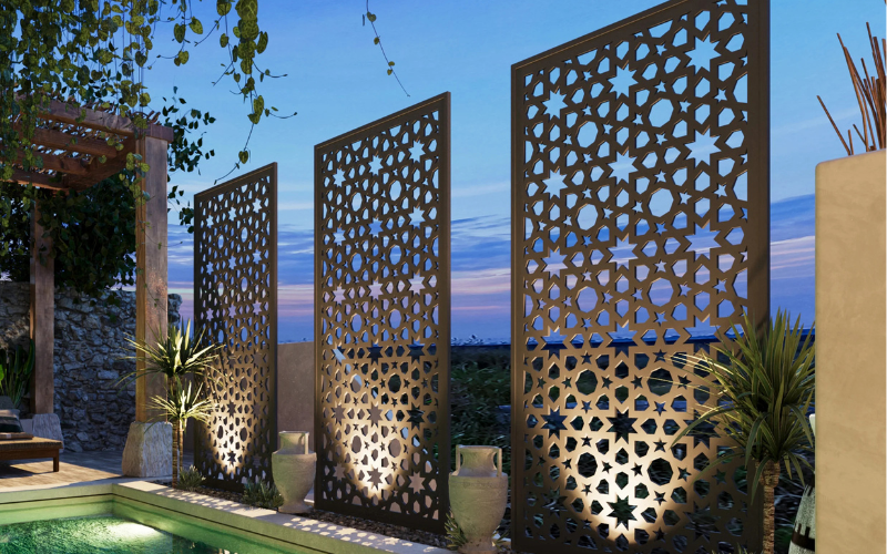 Decorative metal screens with intricate patterns in a garden setting.