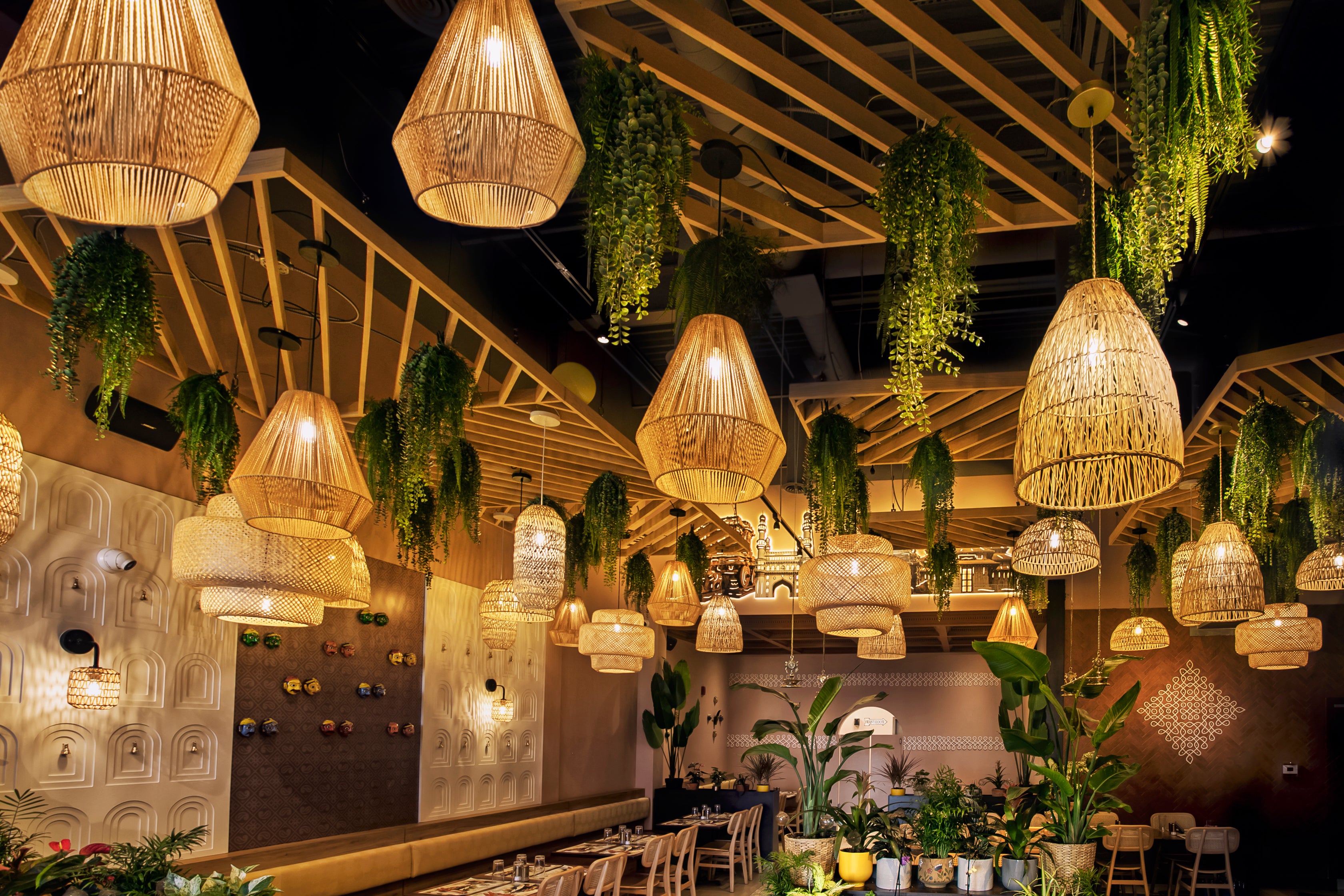 Indoors restaurant setting with hanging wicker lamps and greenery