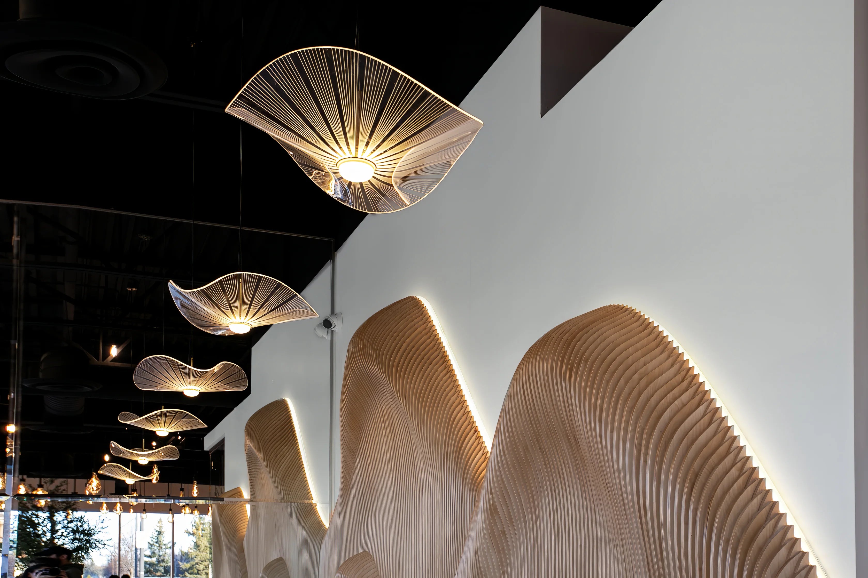 Modern ceiling lights with a wavy design in a room setting.