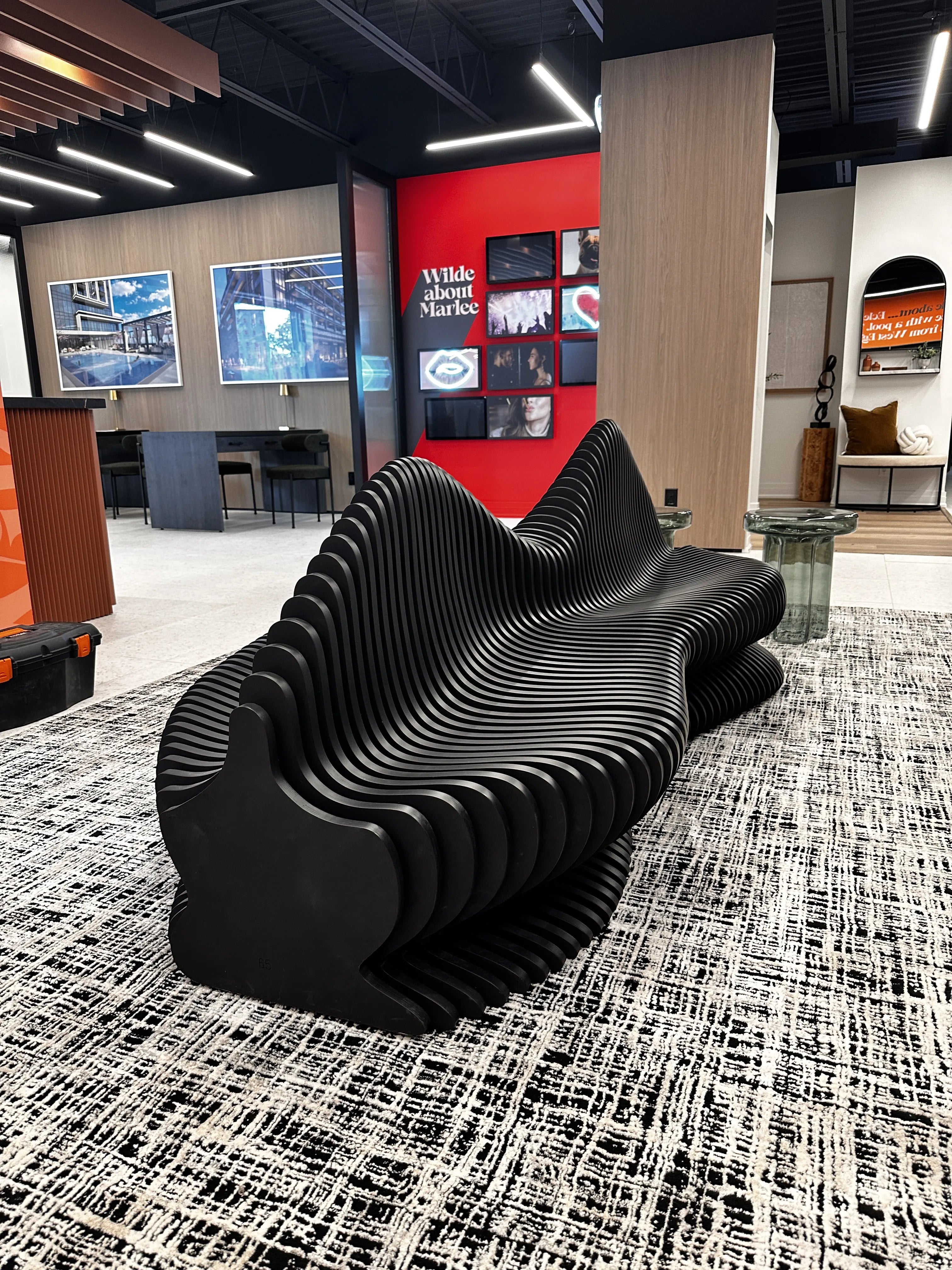 Modern black bench in a stylish interior setting with a red wall and artwork.