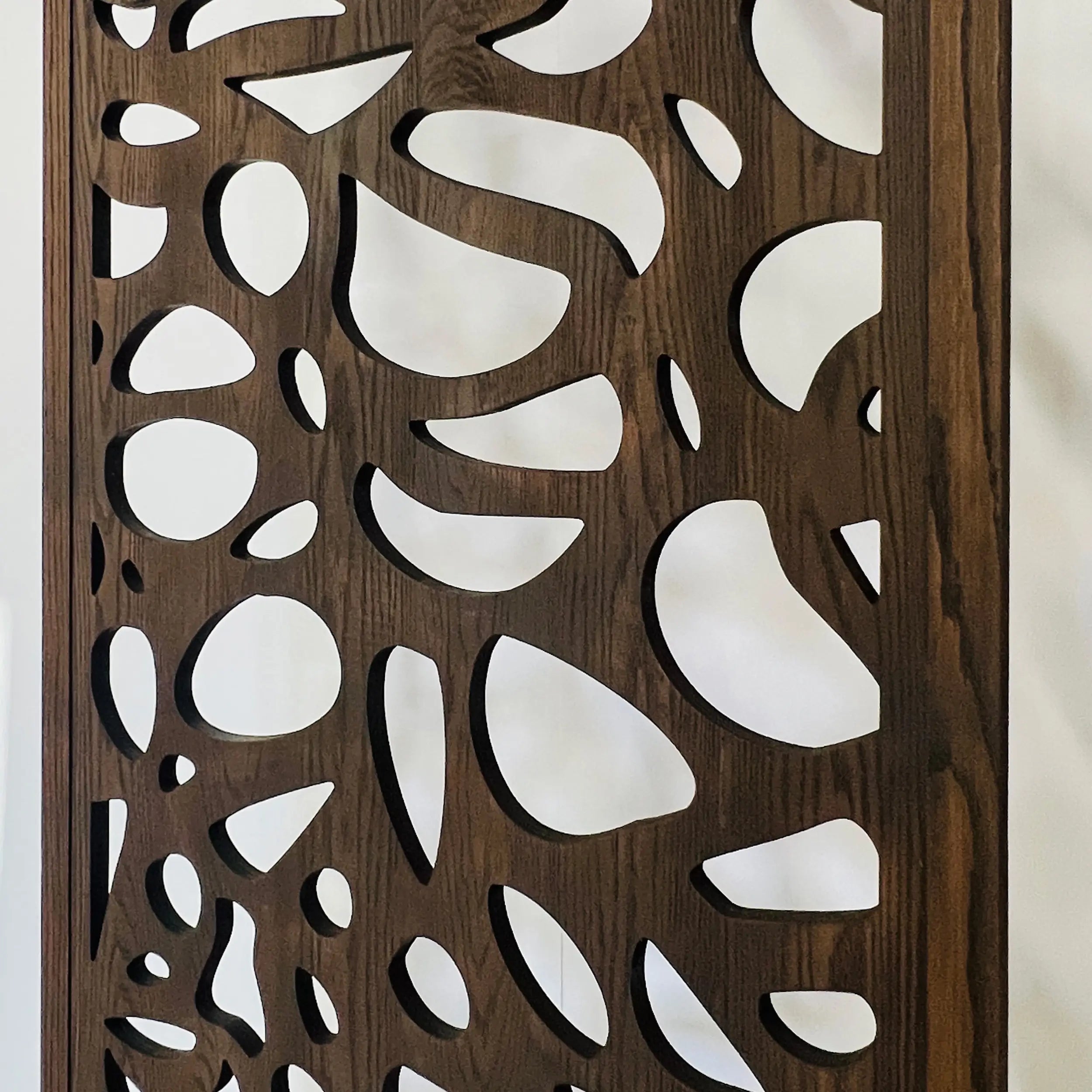 Decorative wall panel with a wooden frame and white cut-out shapes.