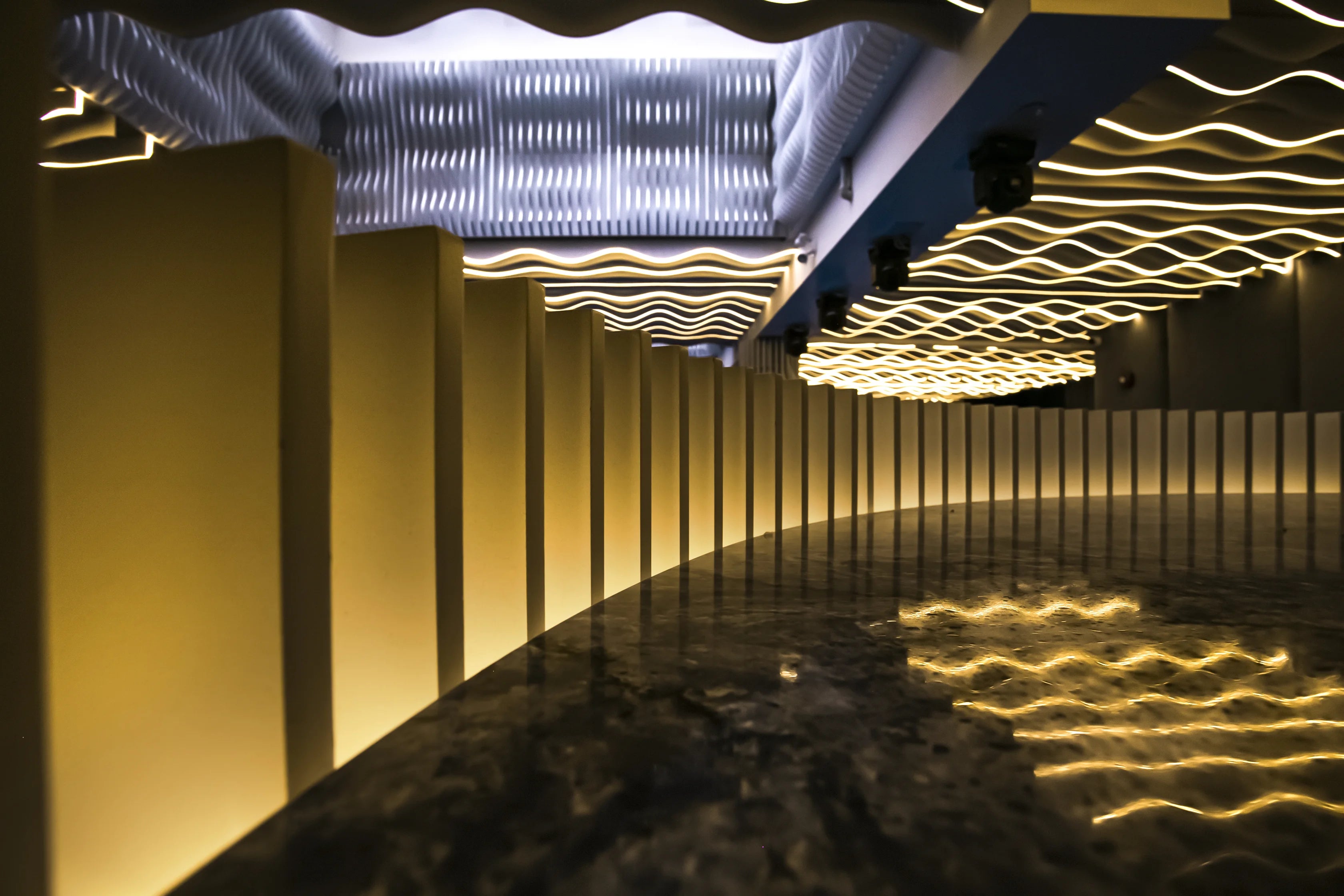 Modern interior design with wavy ceiling lights and floor patterns.