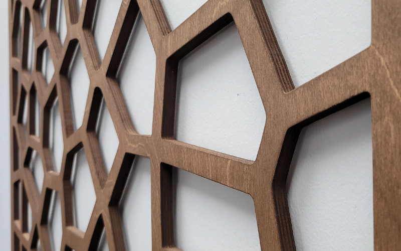 Close-up of a wooden decorative panel with geometric cut-out design on a white background