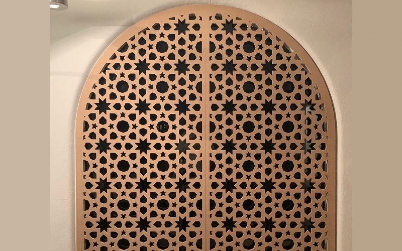 Decorative wooden panel with geometric pattern on a beige wall