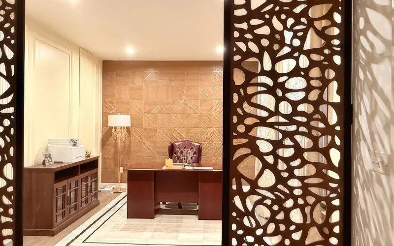 Decorative torus pattern screen with cut-out patterns in a room with a desk and lamp.