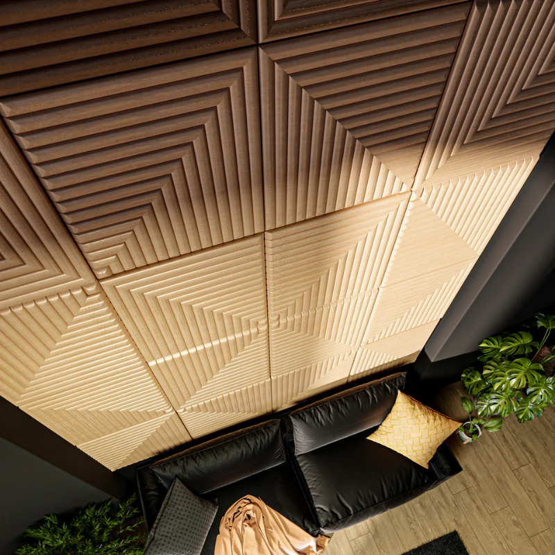 Ceiling with geometric patterned tiles and a black sofa with a yellow pillow.