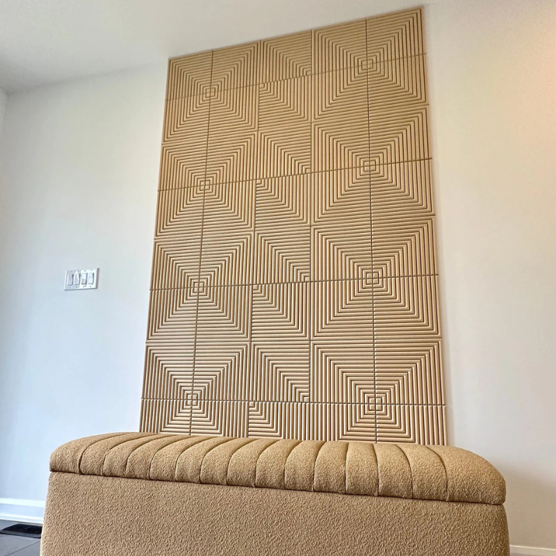 Beige textured acoustic wall panel with geometric pattern above a beige cushioned ottoman.