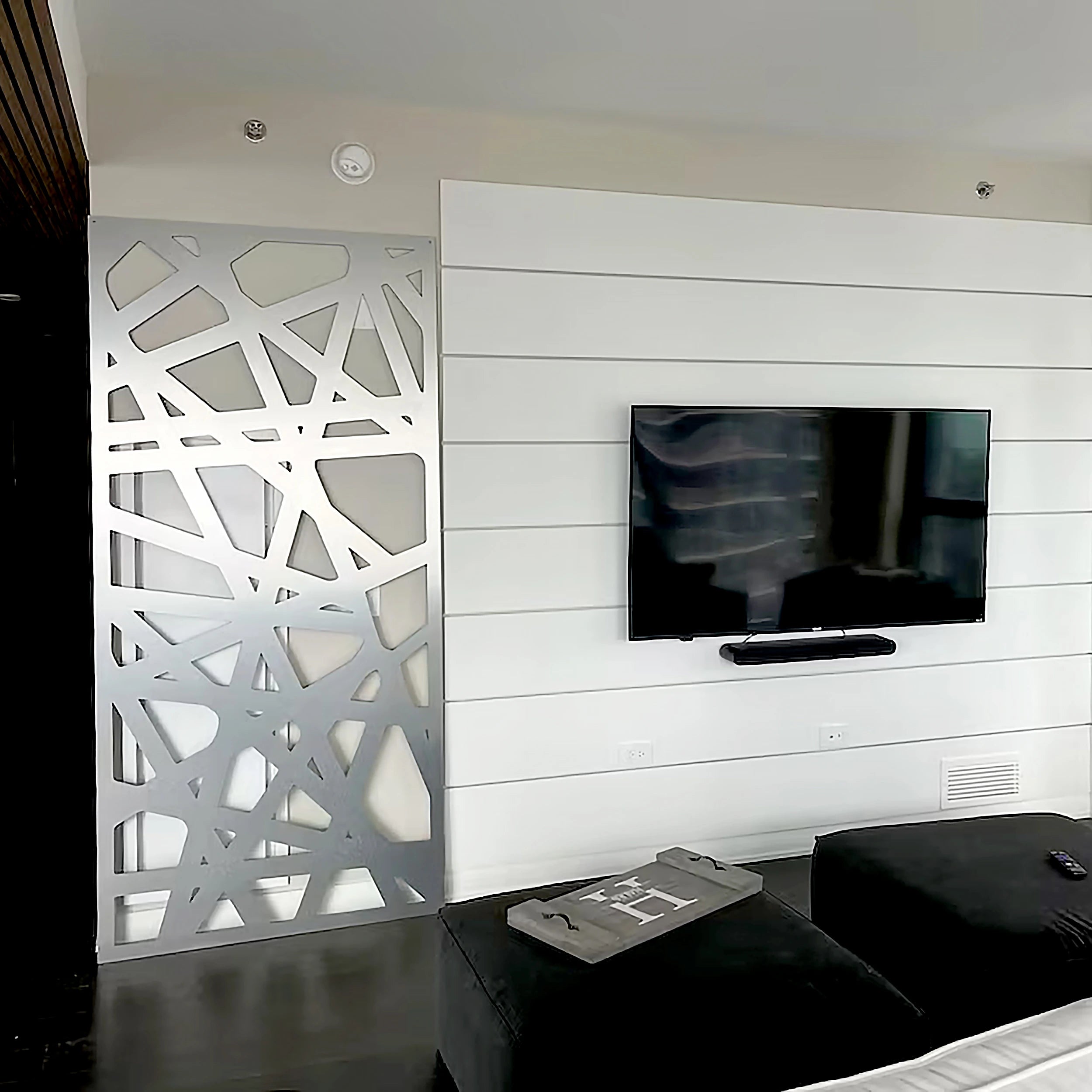 Modern living room with a TV mounted on a white paneled wall, featuring a decorative screen.