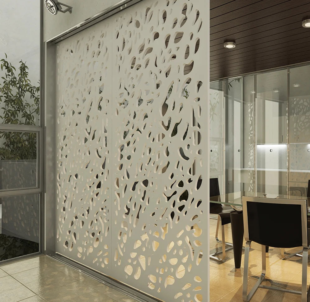 Decorative perforated wall in a modern interior setting with chairs and tables.