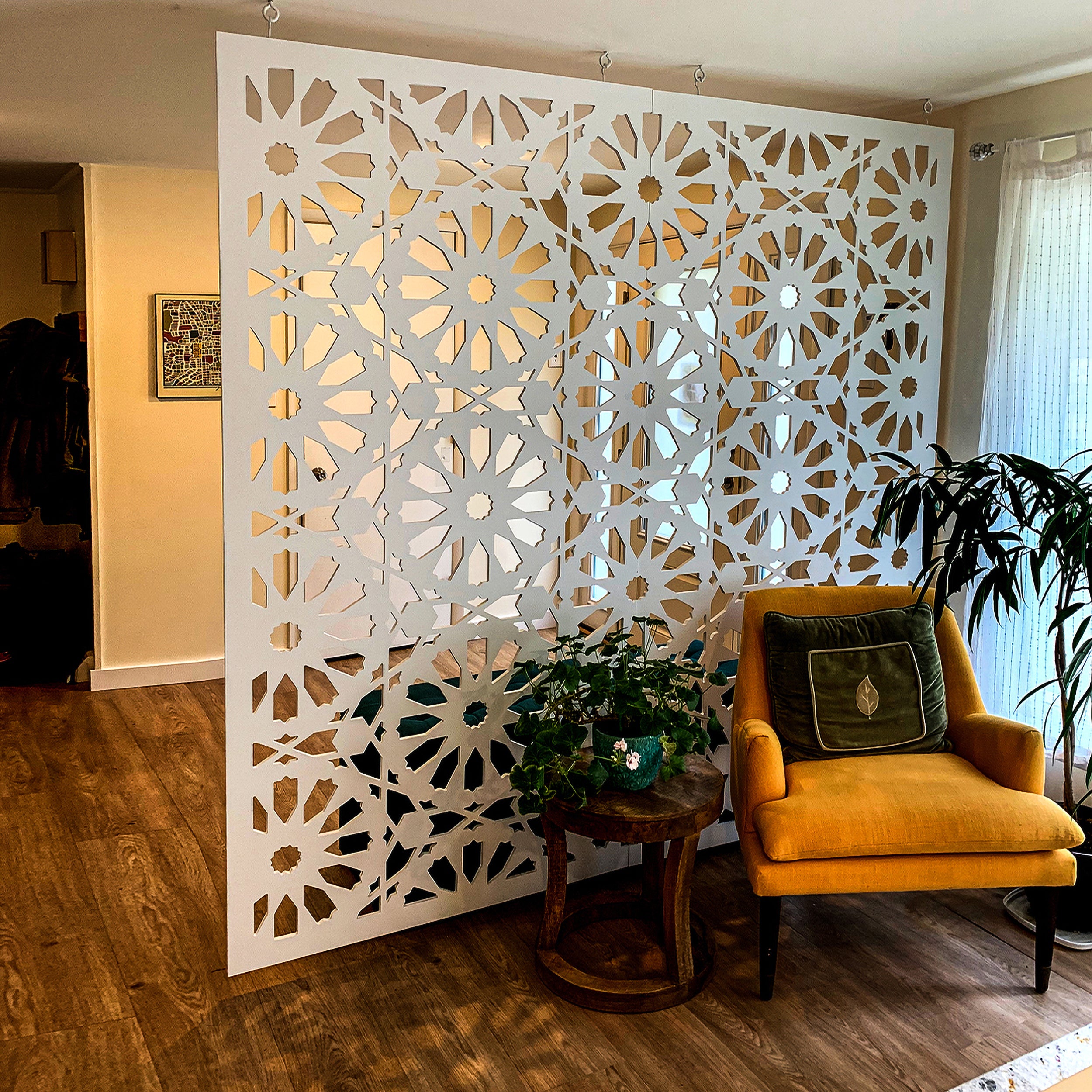 Decorative room divider in a living room with a yellow armchair and plants.