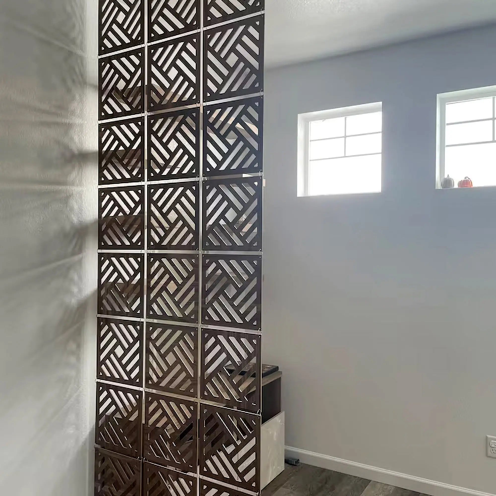 Decorative wall panel with geometric pattern in a room with light blue walls and windows.