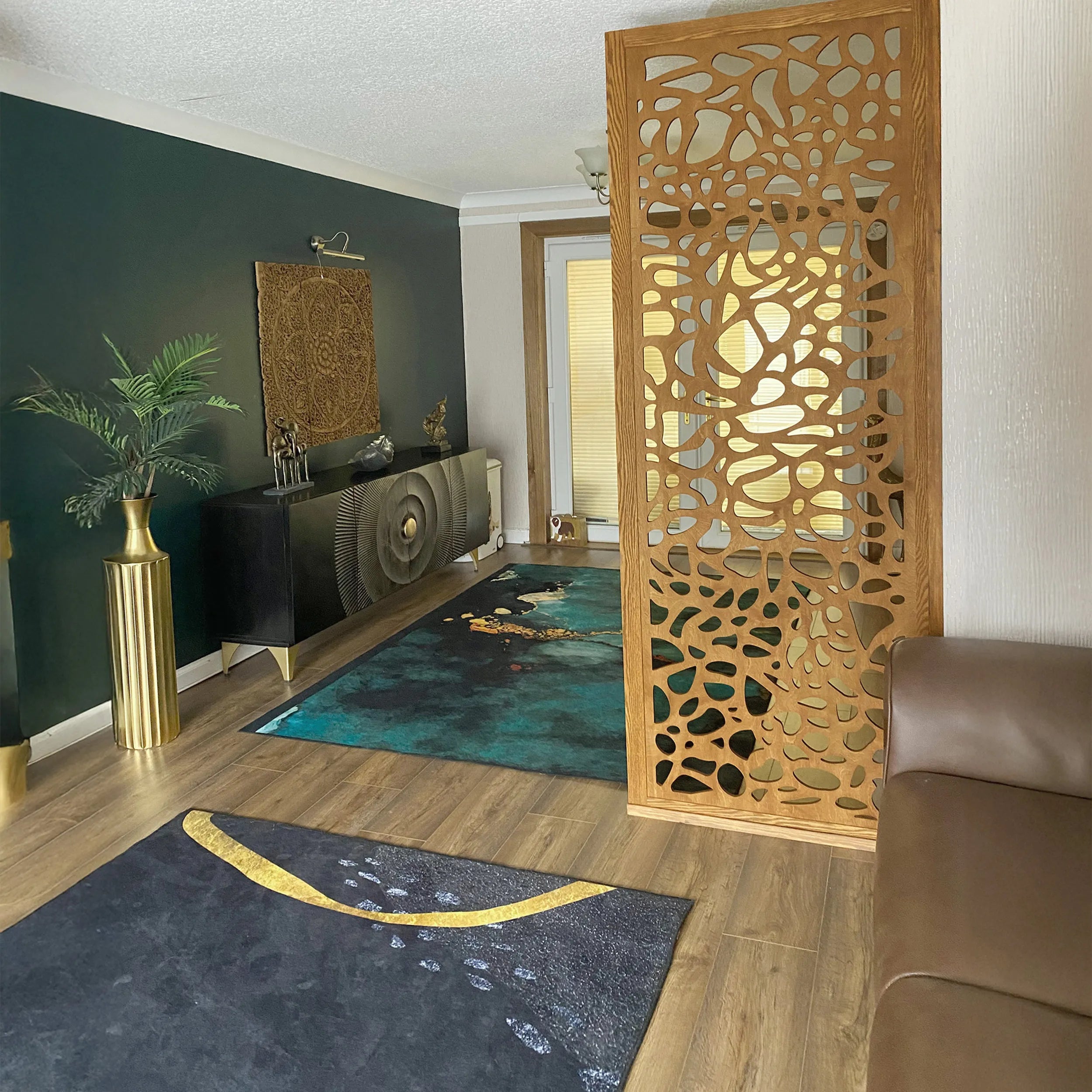 Decorative wooden privacy screen in a living room with a dark green wall, gold vase, and patterned rug.