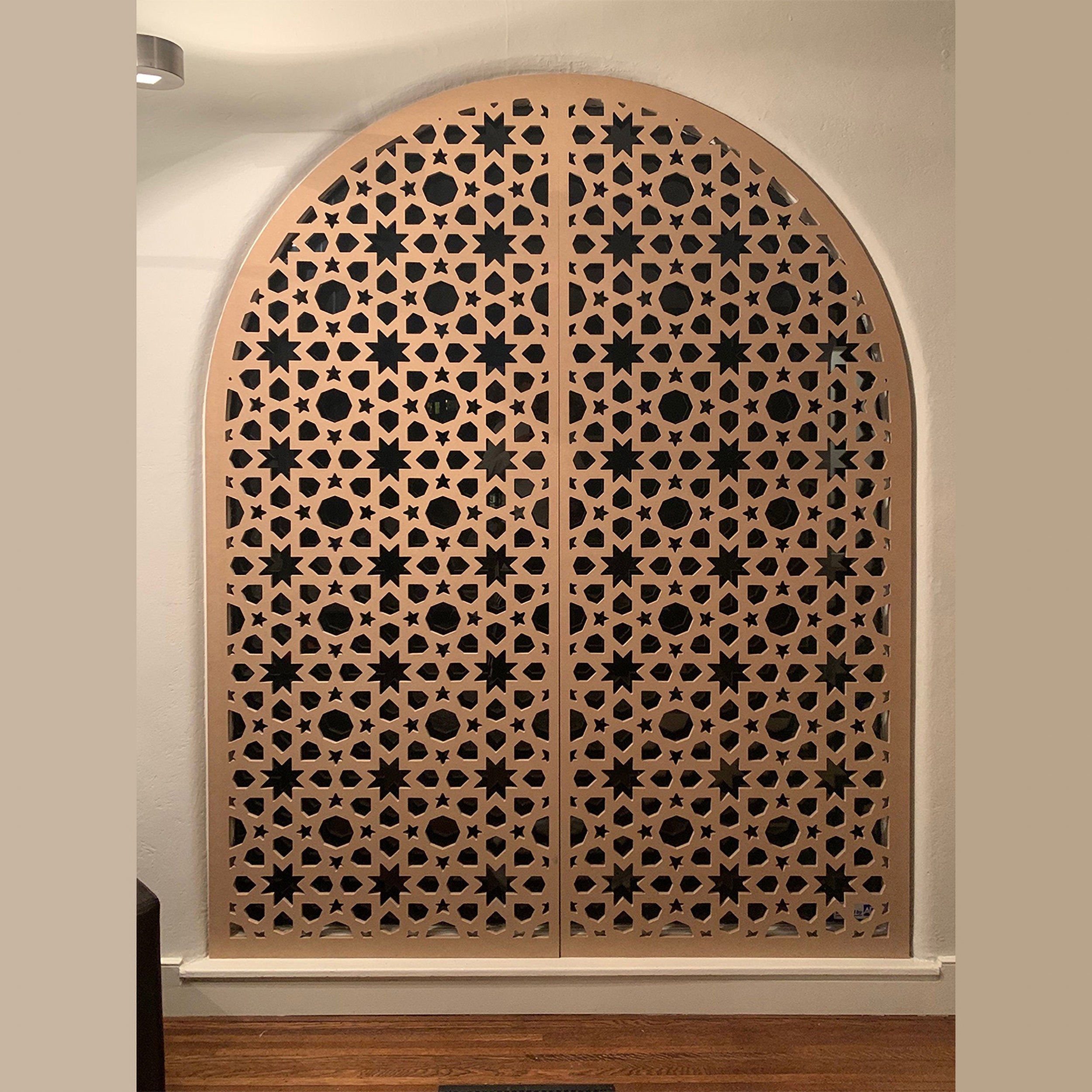 Decorative wooden panel with intricate cut-out patterns on a beige wall.