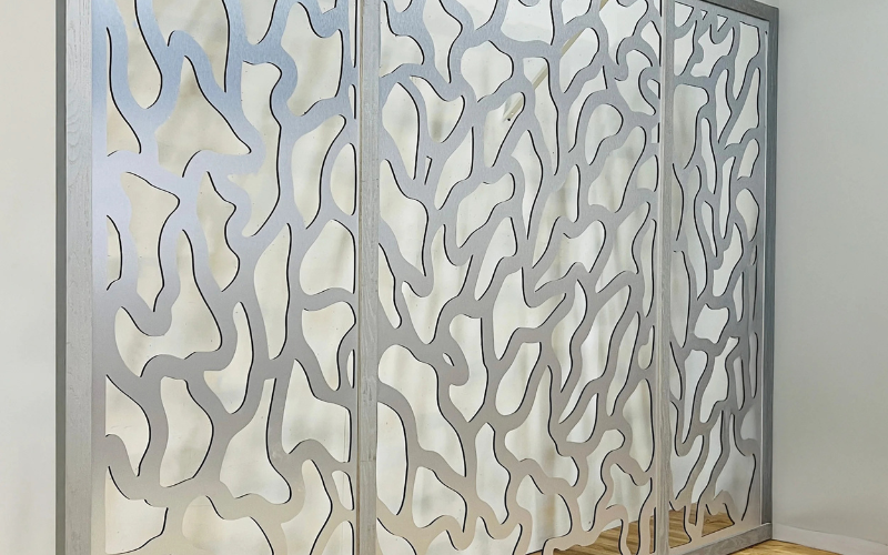 Decorative wall panel with intricate cut-out patterns in a room setting.