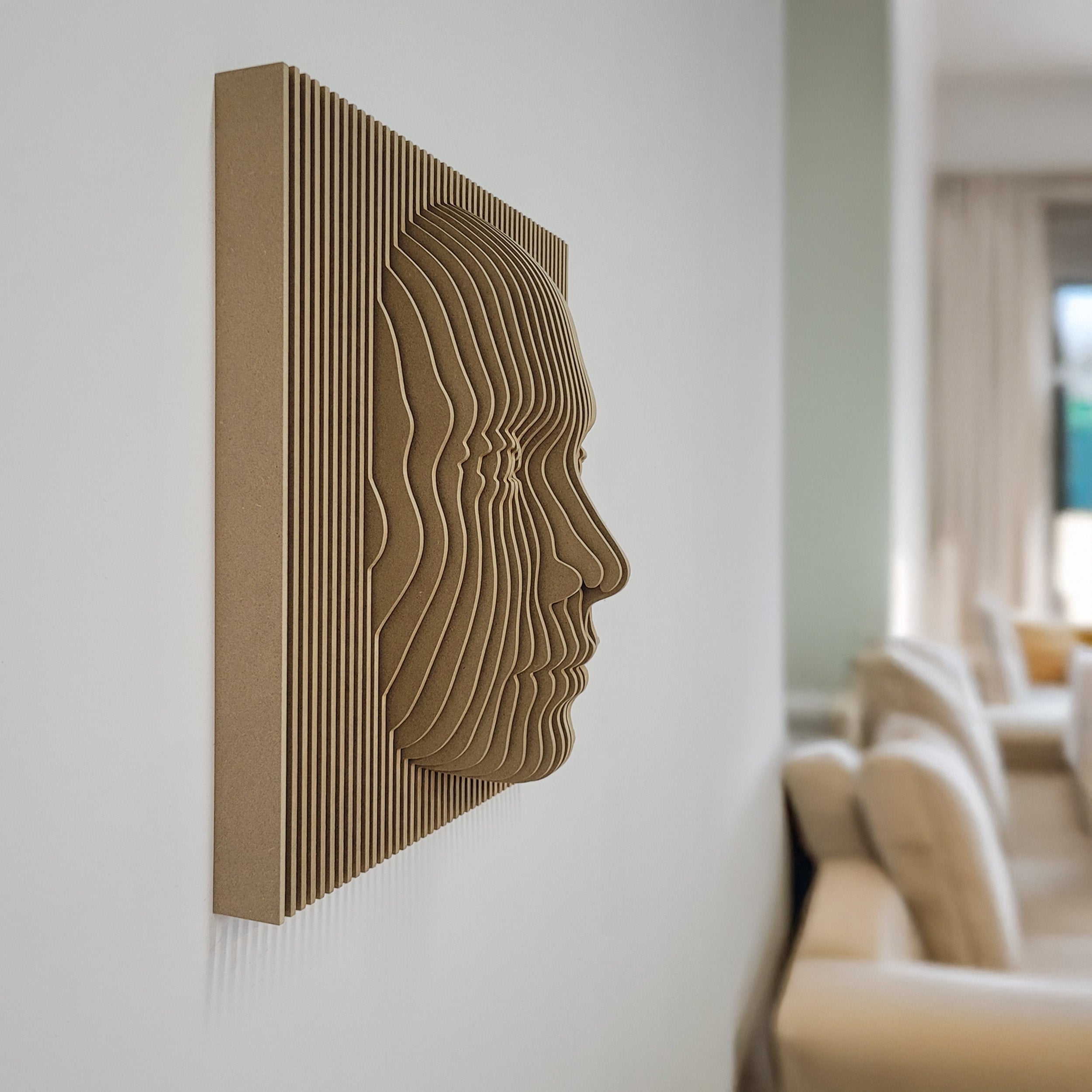 Decorative wall art with a textured face design on a white wall.