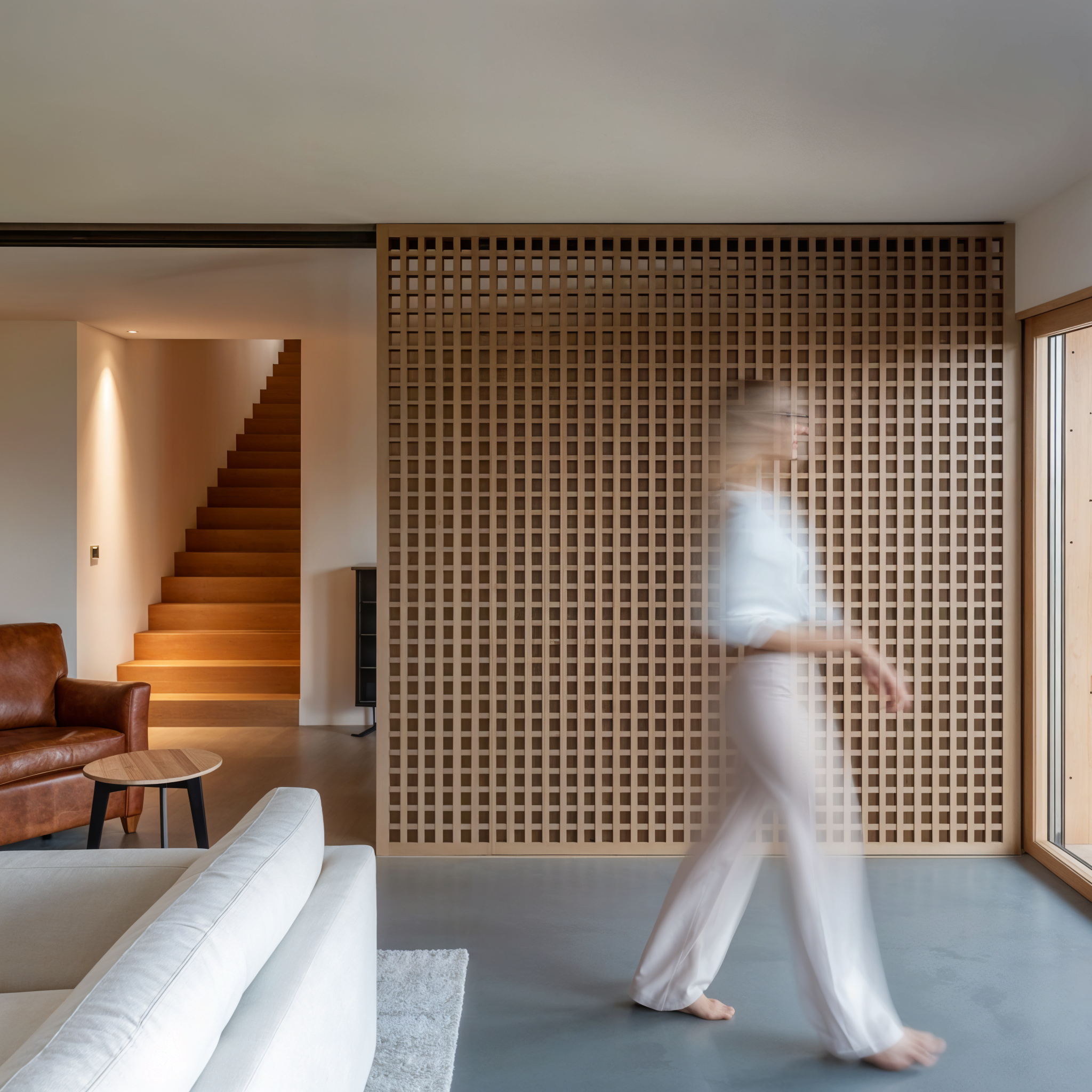 Person walking through a modern living room with a lattice wall.